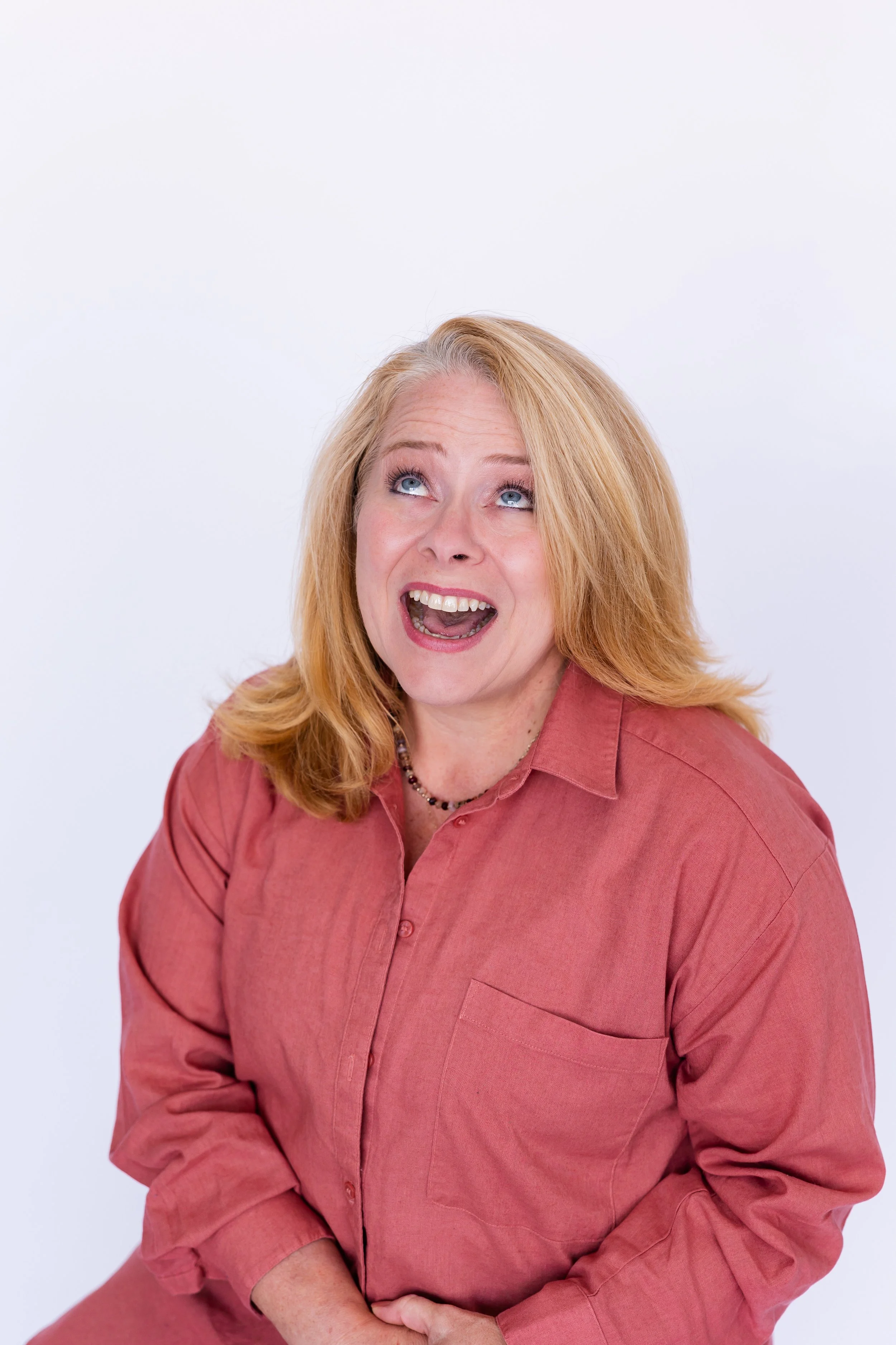 Lisa Summers, life coach, with blonde hair, blue eyes, wearing a pinkish-coral shirt, smiling, against a plain white background.