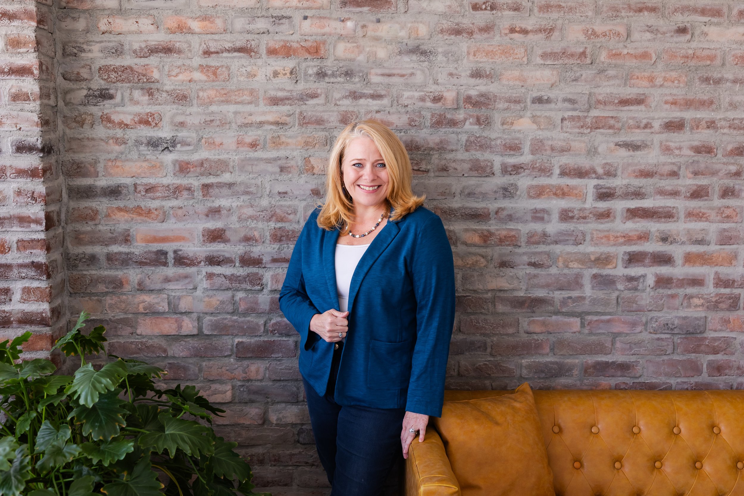 Founder and wellness coach Lisa Summers standing next to a yellow sofa