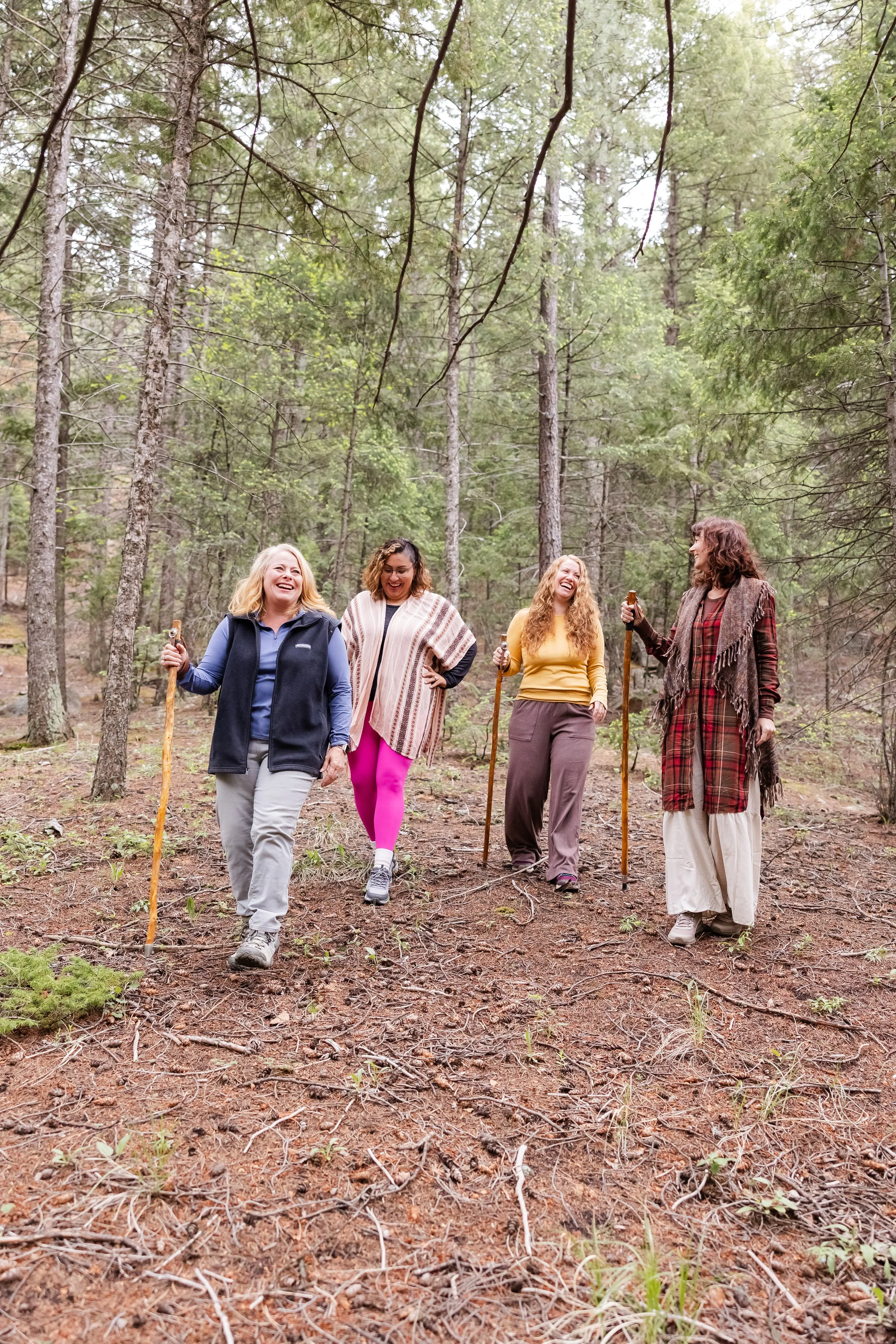 Four women hiking in a forest, on women's wellness retreat in the Colorado mountains.