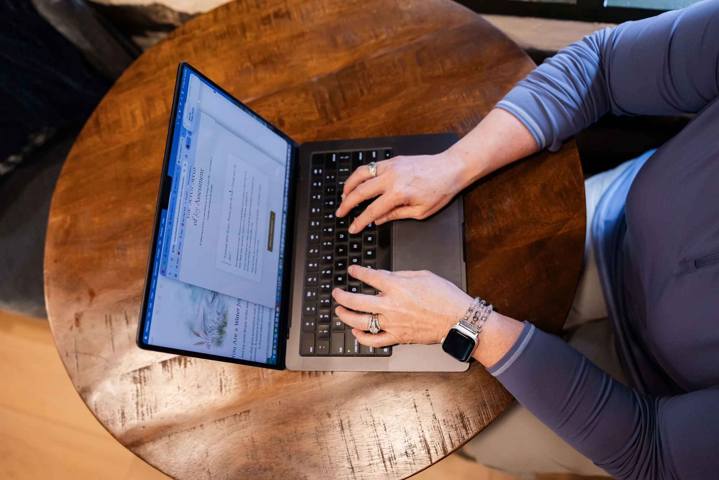 Person using a laptop at a wooden table, scheduling business leadership retreats.