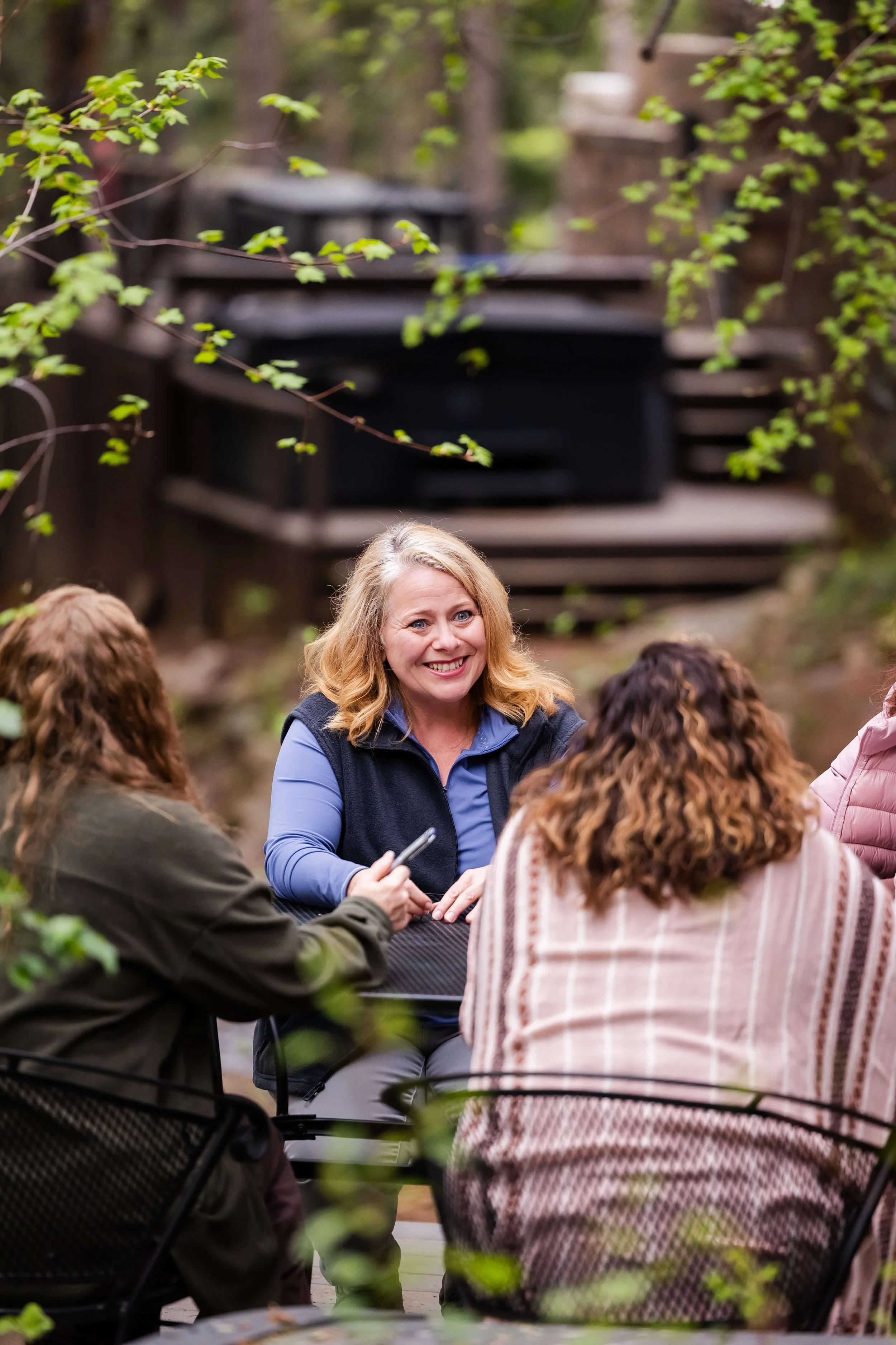 A group of people outside of a cabin, having group coaching session.