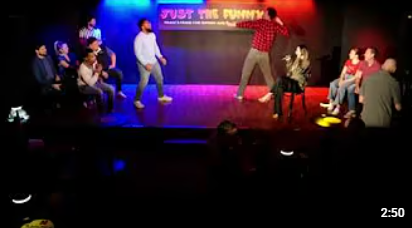 Comedy show on stage with performers and audience members seated nearby