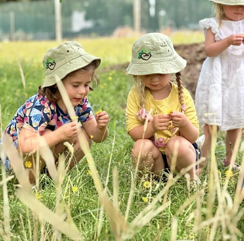 Two girls picking flowers during outdoor play at Country Wonders preschool in Loburn, North Canterbury