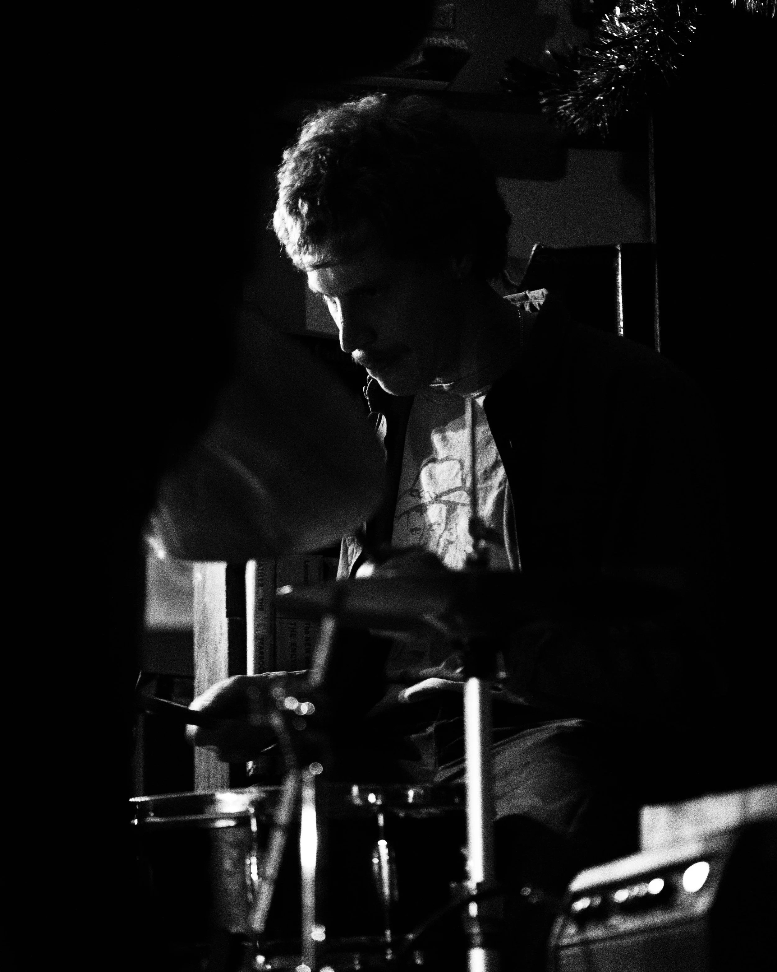 Black and white photo of Steven Douglas playing drums, at Mother Foucault's Bookshop.