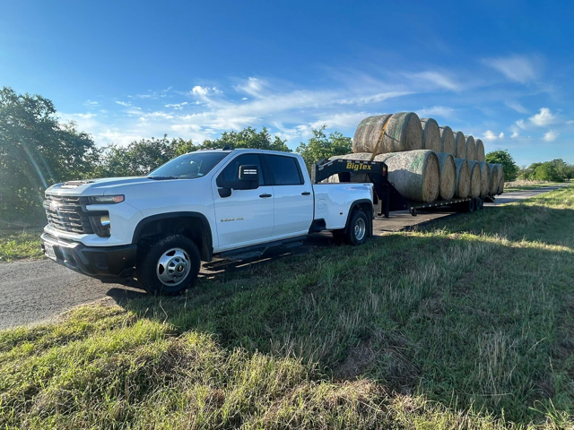 Pickup truck hauling hay bales, representing agricultural supply and transport services.