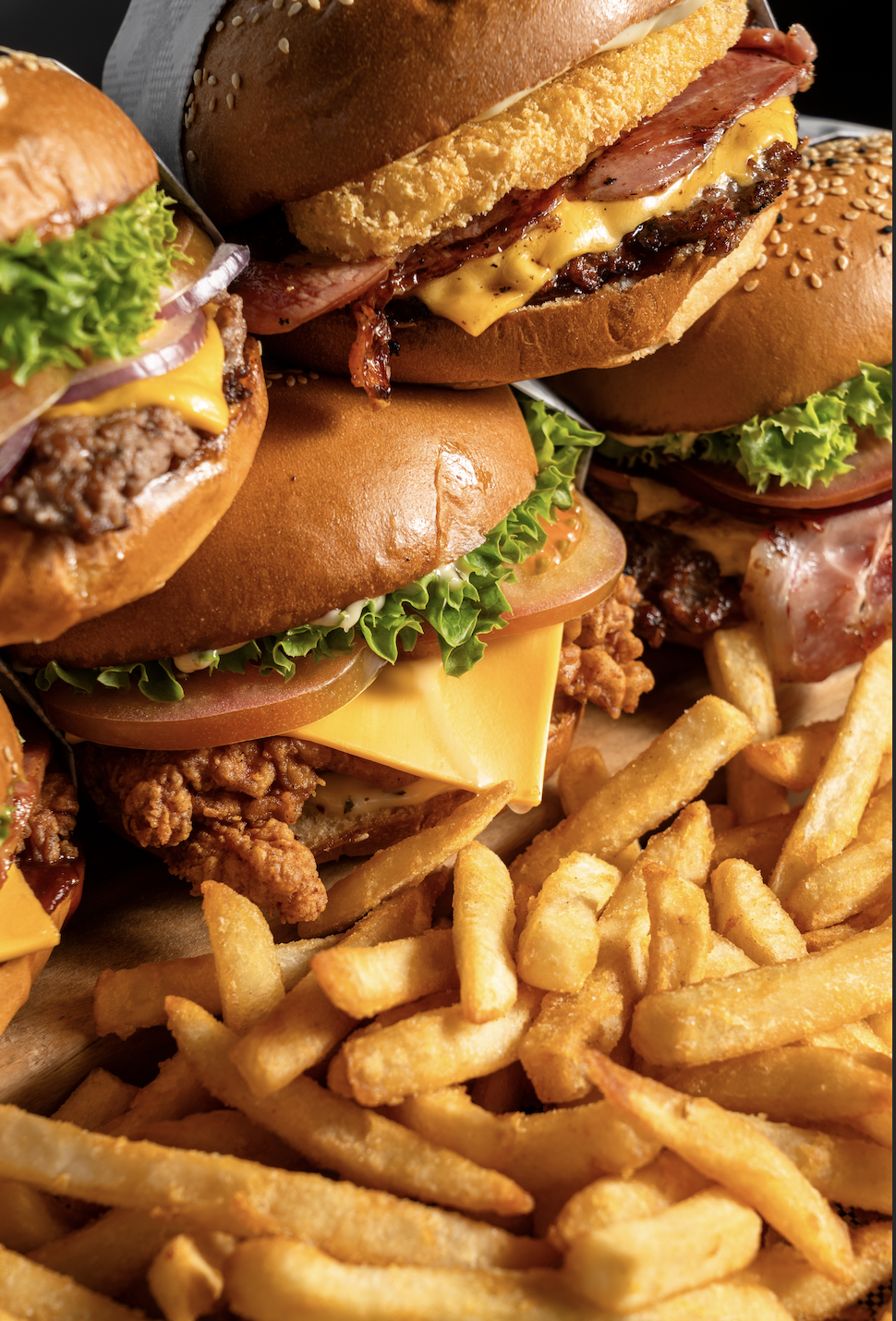 Chicken and beef burgers stacked on a mountain of fries.