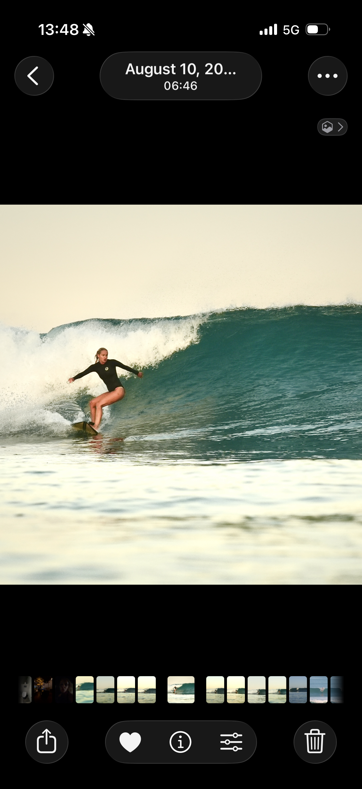A female surfer wearing a black wetsuit rides a wave on a surfboard in the ocean during daytime.