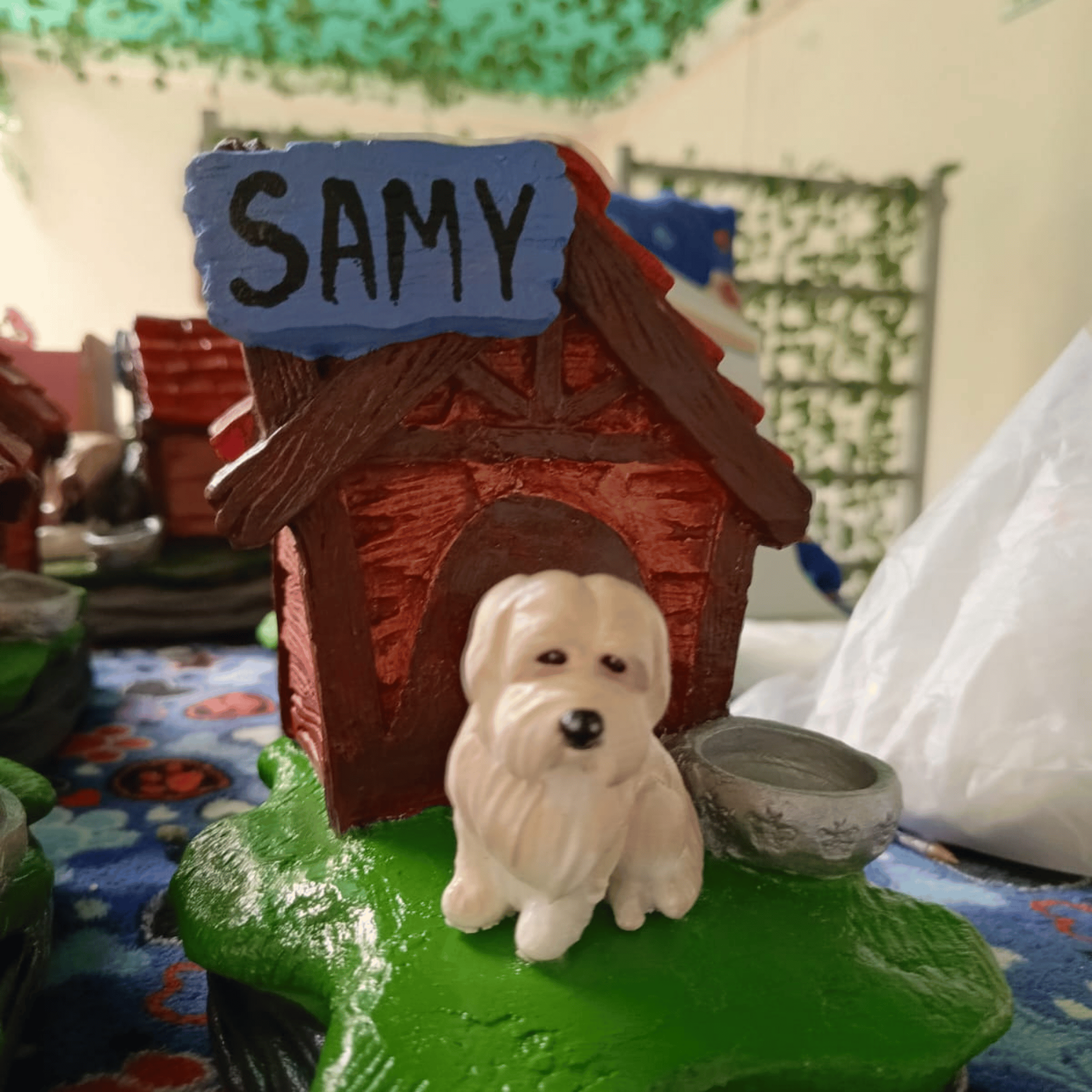 Casa de cerámica con un perro pequeño de cerámica en el frente, y una placa que dice 'SAMY' en la parte superior.