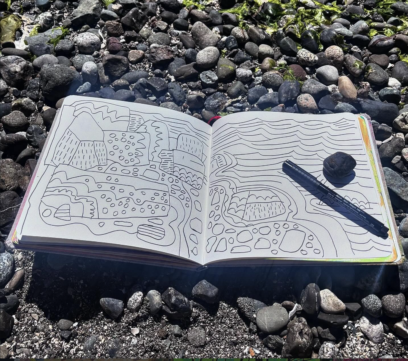 Solevads sketchbook open resting on river rocks at the shore