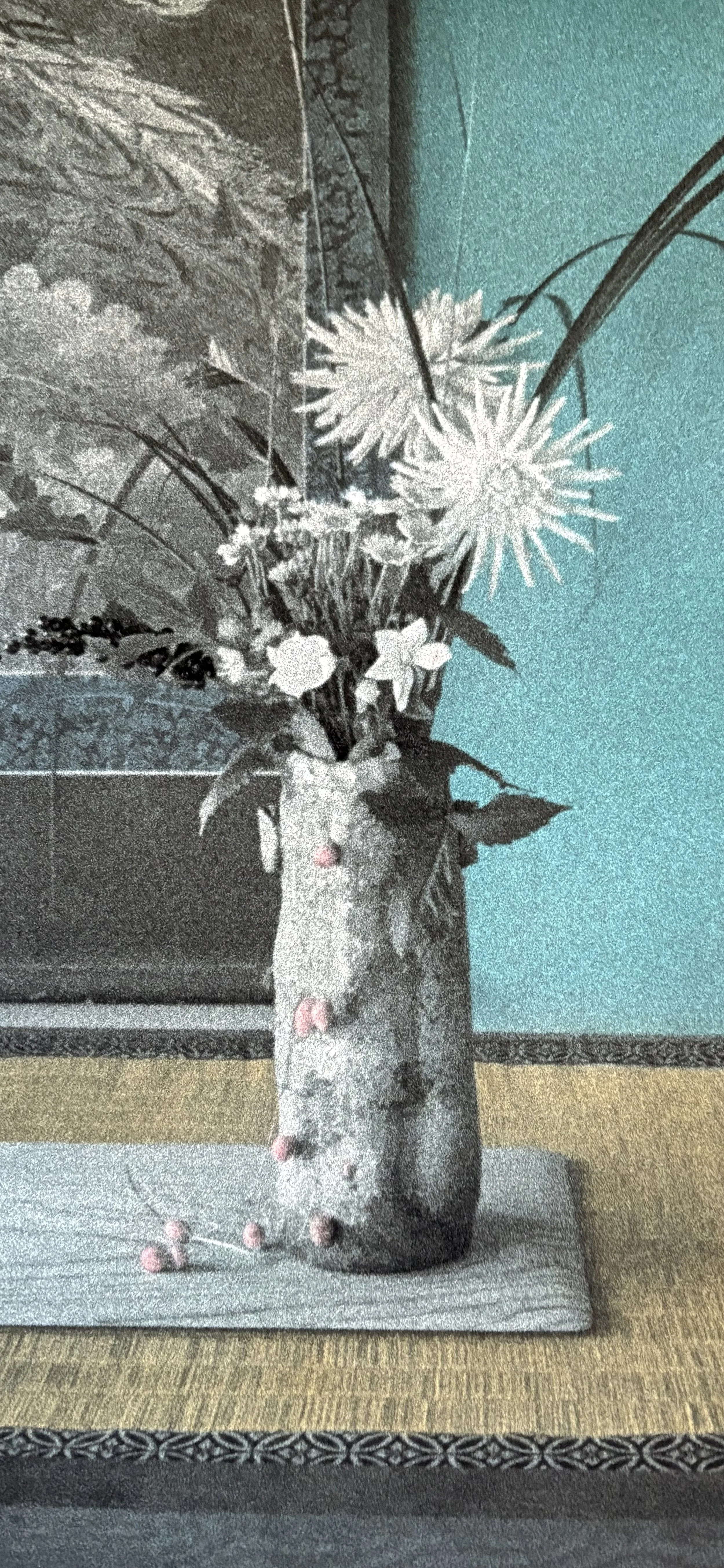A flower arrangement in a vase with pink and white flowers, placed on a wooden surface, against a background with a teal wall.