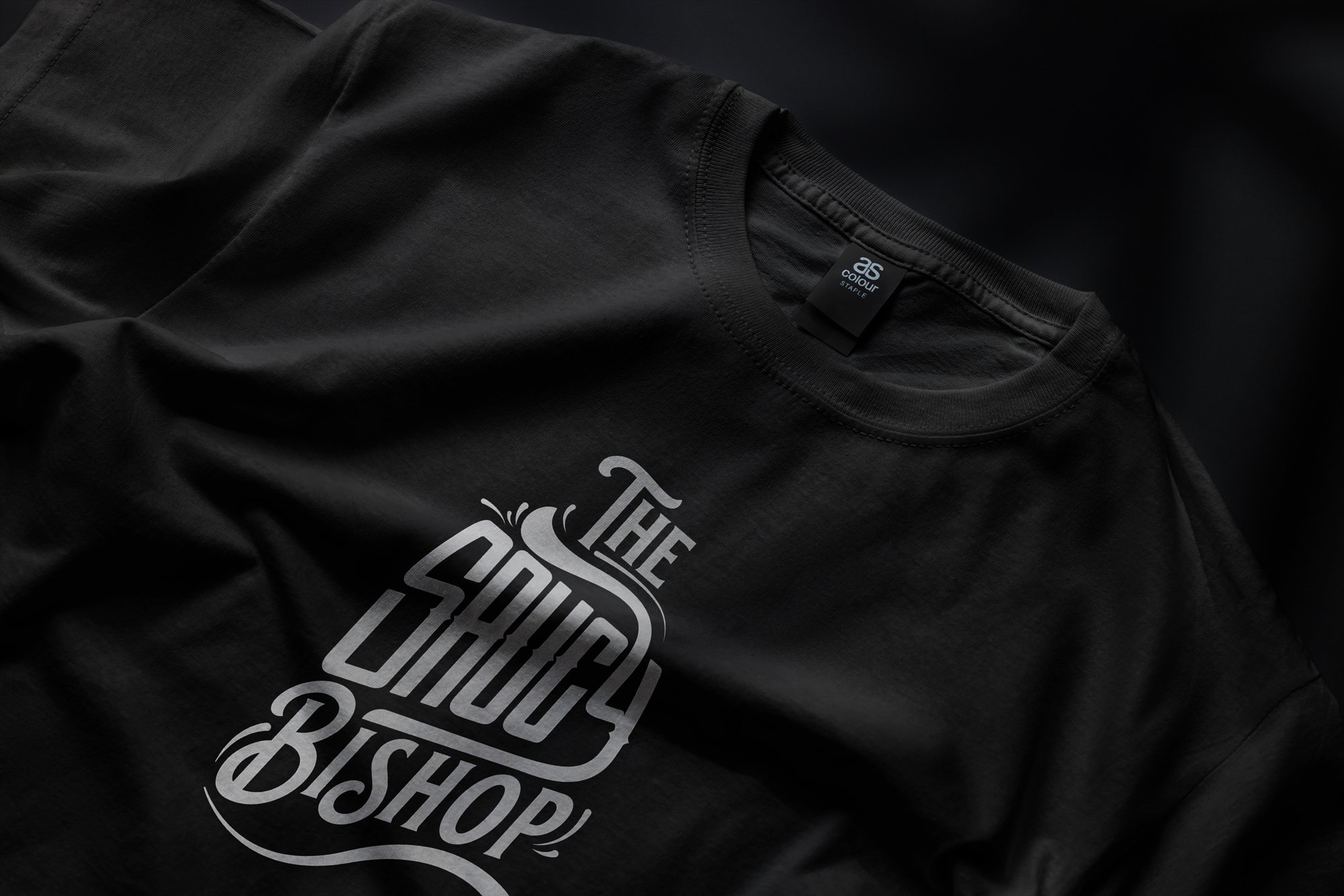 Close-up of a black t-shirt with a Harley Davidson logo in white on the front and a black clothing tag inside the collar.