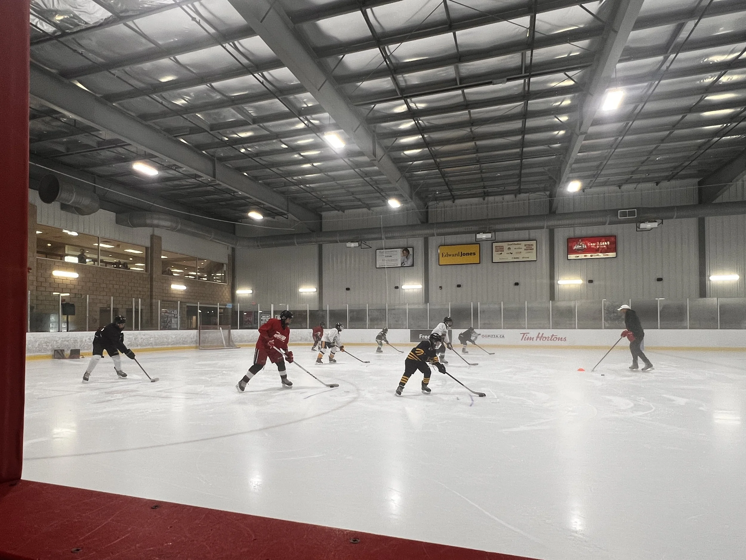 People practicing hockey on an indoor ice rink.