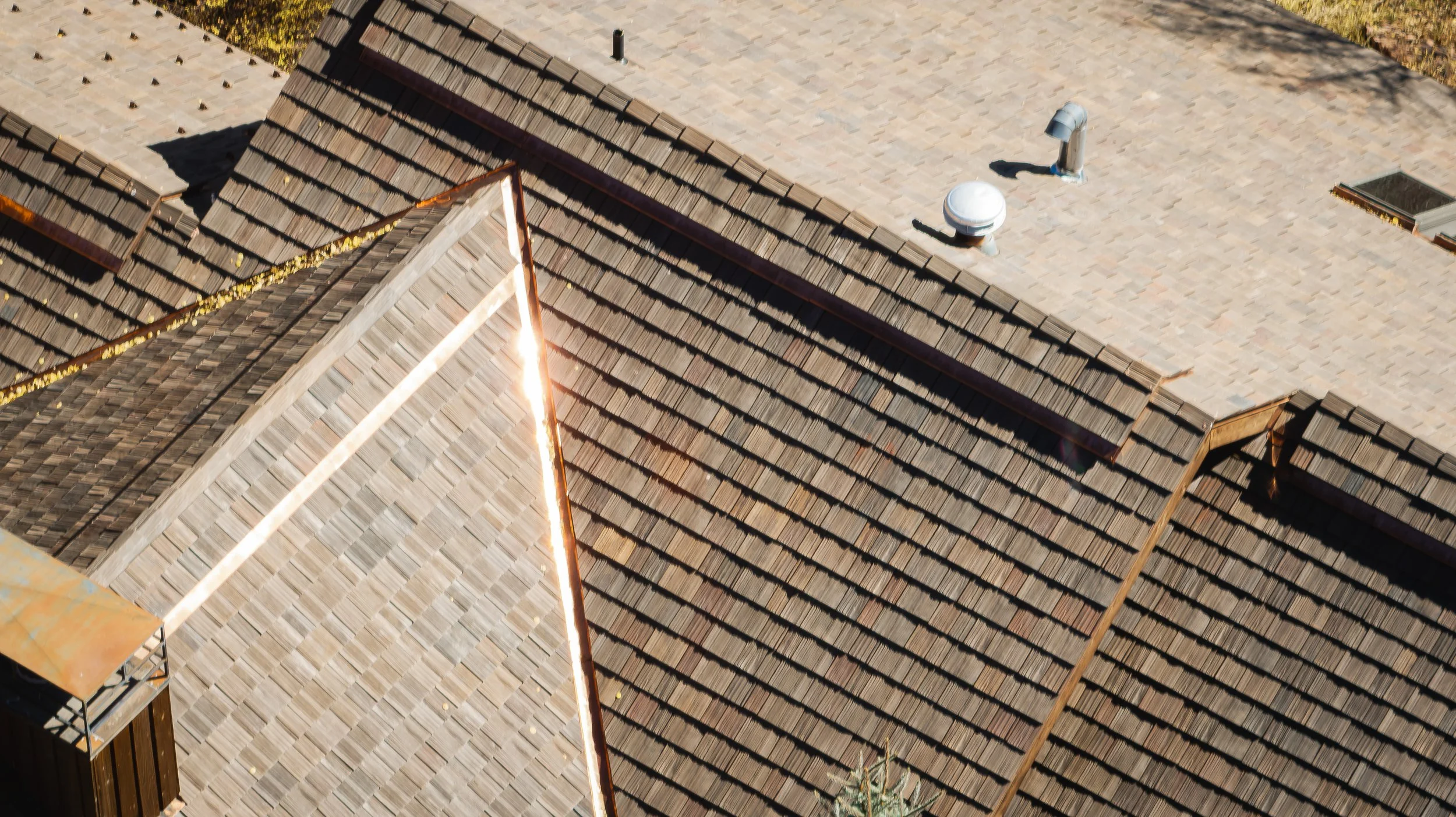 Aerial view of Brava synthetic shake roofing in mixed brown and driftwood tones with copper ridge and valley flashing detail, premium roofing Idaho Mountain West
