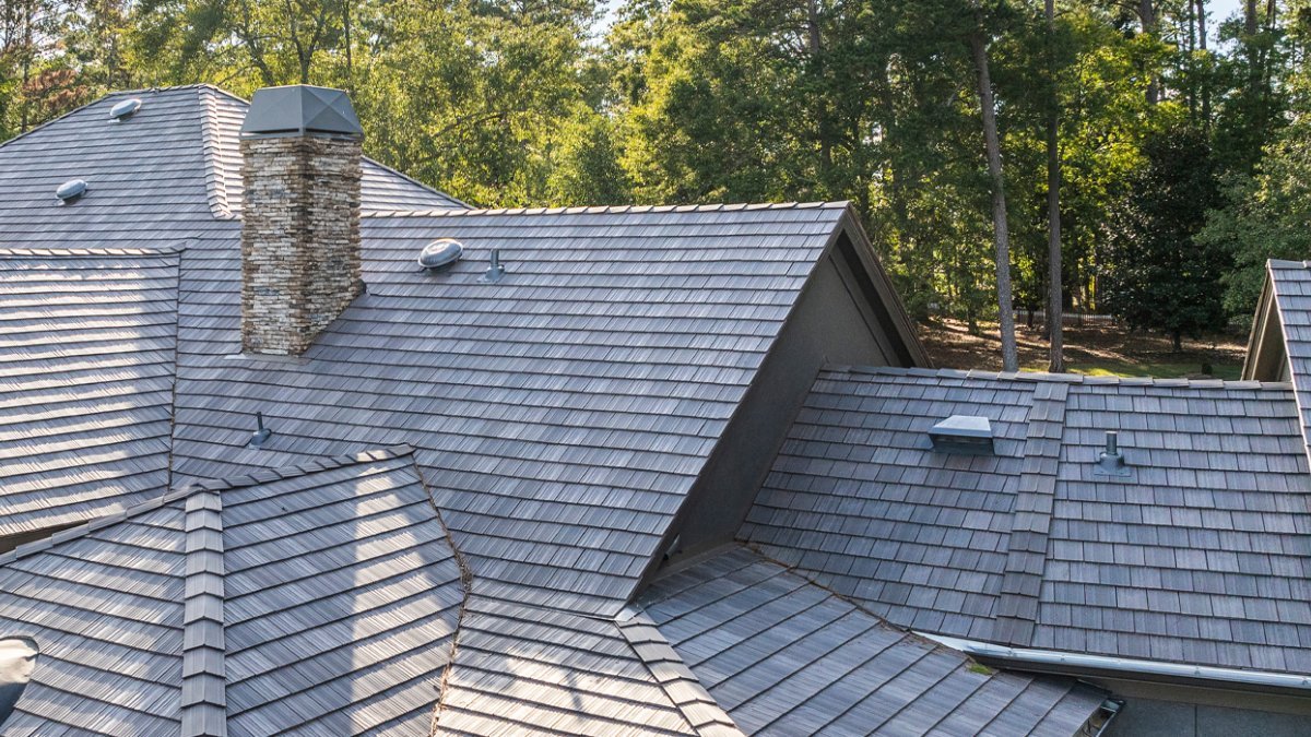  DaVinci synthetic slate roofing in weathered gray on a multi-pitch residential roofline with stone chimney, premium roofing contractor Idaho Mountain West