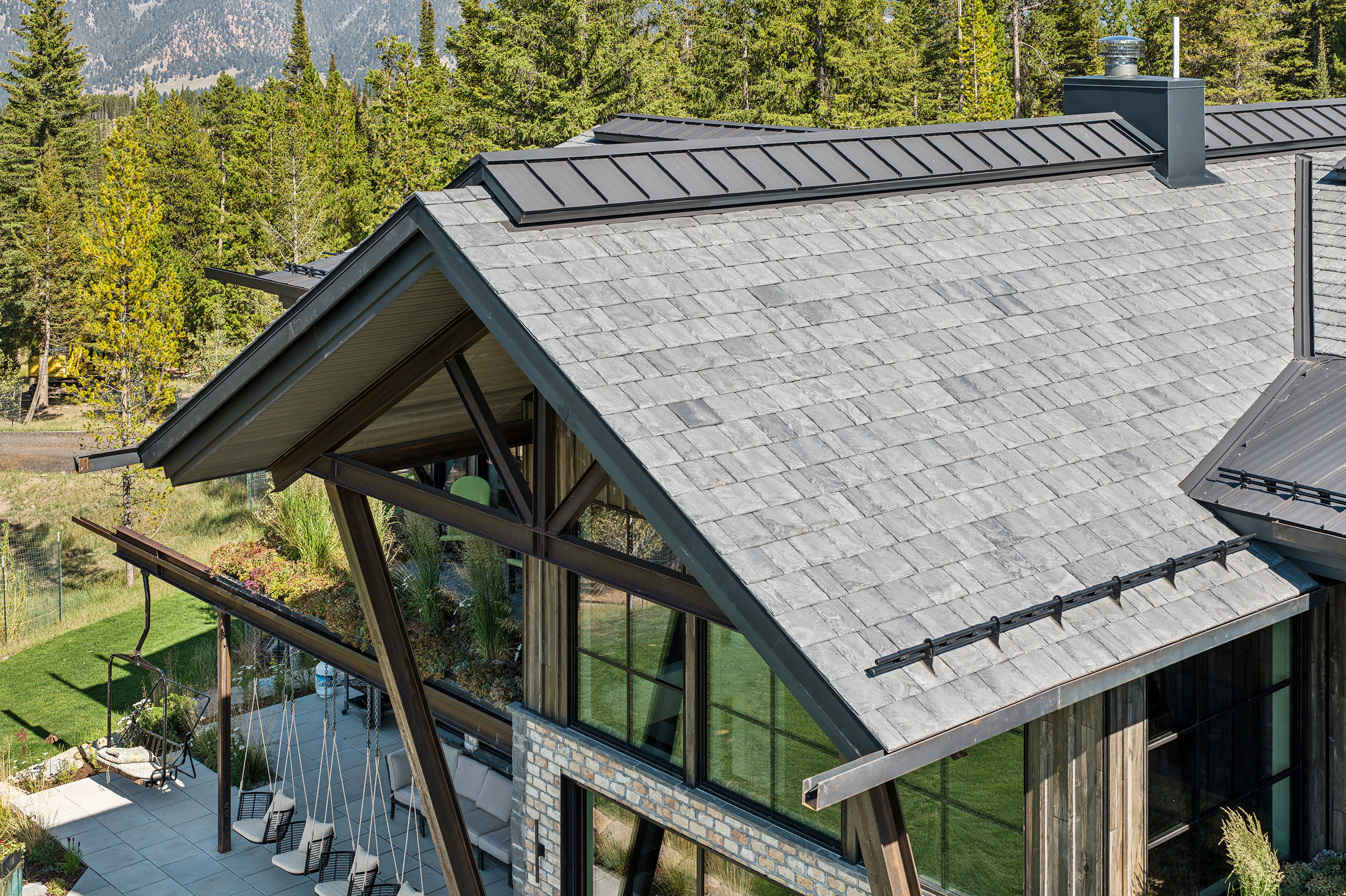 Brava synthetic slate roofing on a contemporary mountain lodge with exposed timber framing and floor-to-ceiling windows, resort roofing Idaho