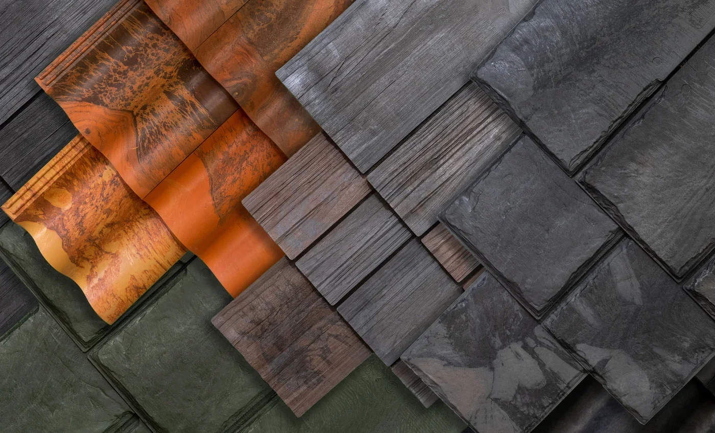 A display of stacked roofing materials, including slate, wood, and metal shingles in various colors and textures.