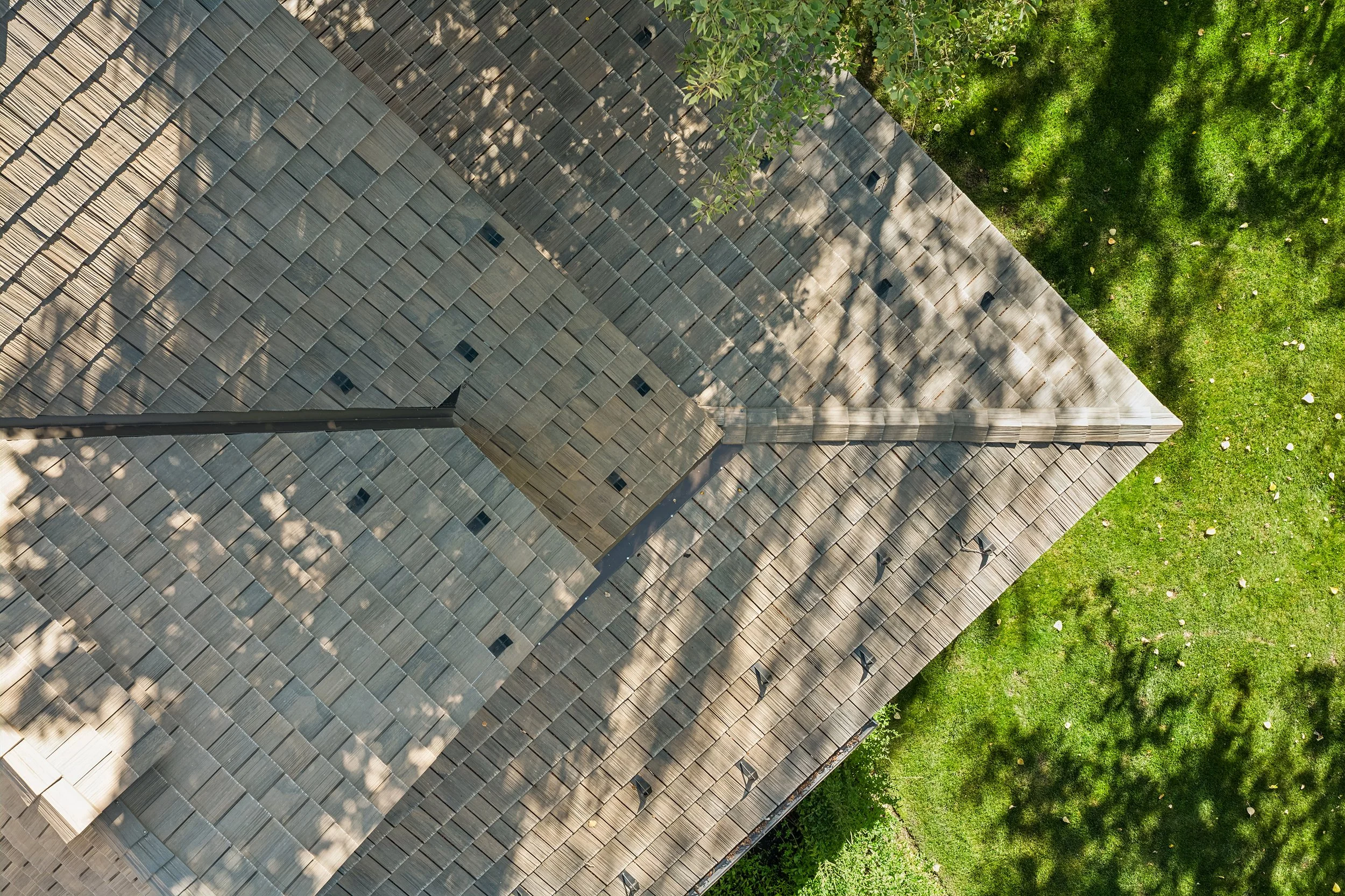 Aerial view of Brava synthetic shake roofing in driftwood and sand tones with precise valley flashing and tree shadow detail, specialty roofing contractor Mini-Cassia and Sun Valley Idaho