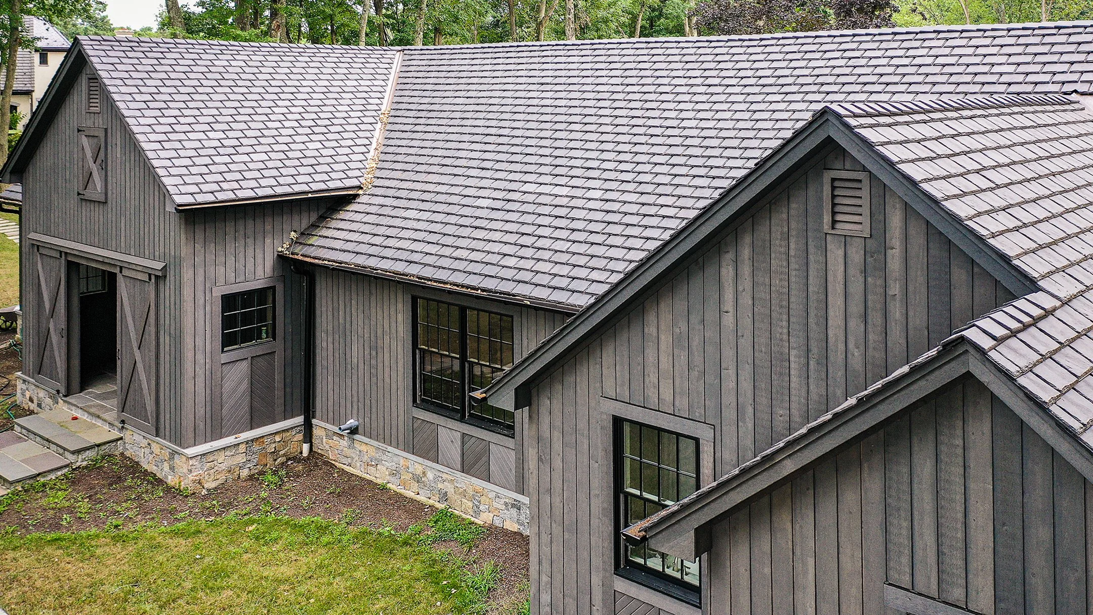 Brava Slate roofing in weathered gray on a contemporary farmhouse structure surrounded by mature trees on stone foundation, specialty roofing Idaho Mountain West