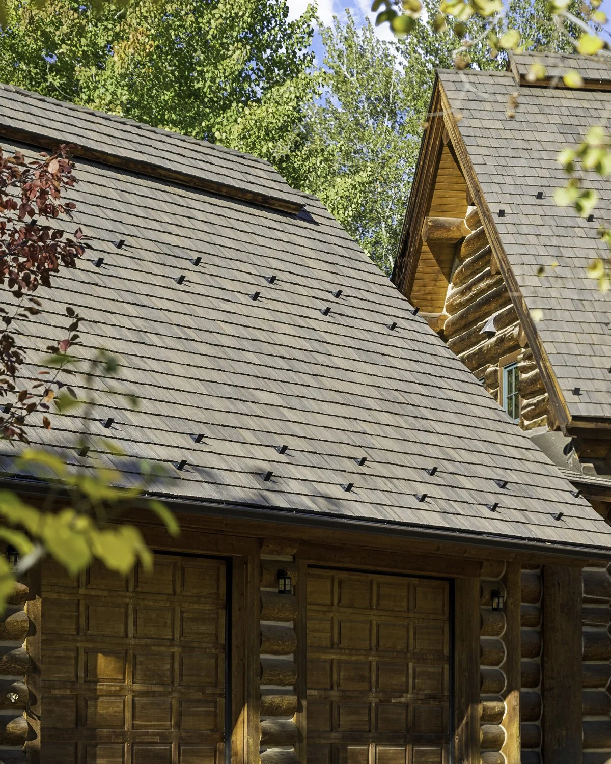 Brava synthetic shake roofing installed on a log cabin home surrounded by mature trees, Idaho Mountain West, Sun Valley