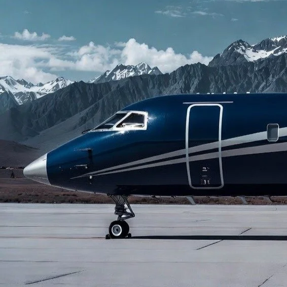 Close-up of a blue commercial airplane on a runway with snow-capped mountains in the background.
