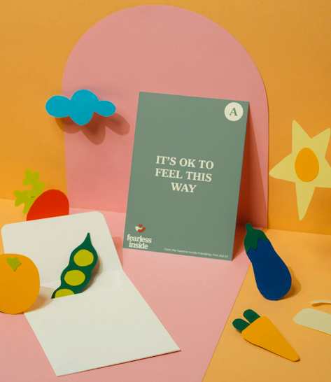 Colorful paper cutouts of vegetables, a motivational card, and decorative shapes on a pink and yellow background.