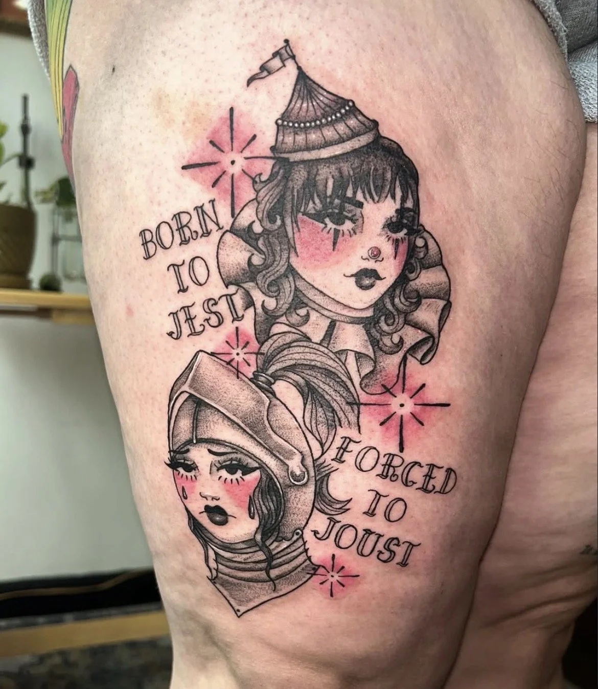 Tattoo of two stylized women's portraits with pink blush and eyelashes, intertwined with text that reads 'Born to Test' and 'Forced to Joust', surrounded by starburst designs.