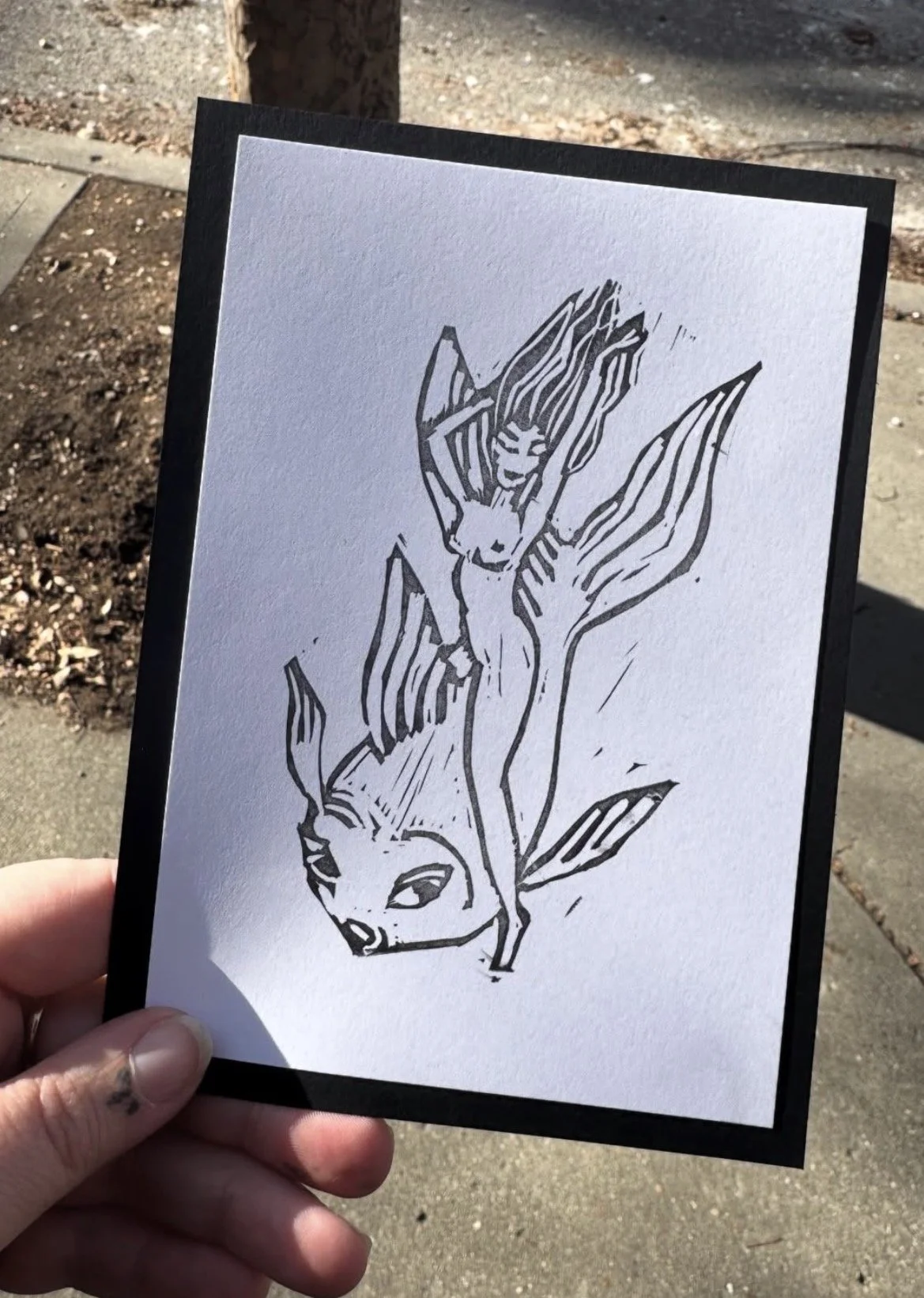 Black and white illustration of a fox with large floral elements in the style of a tattoo design, held outdoors.
