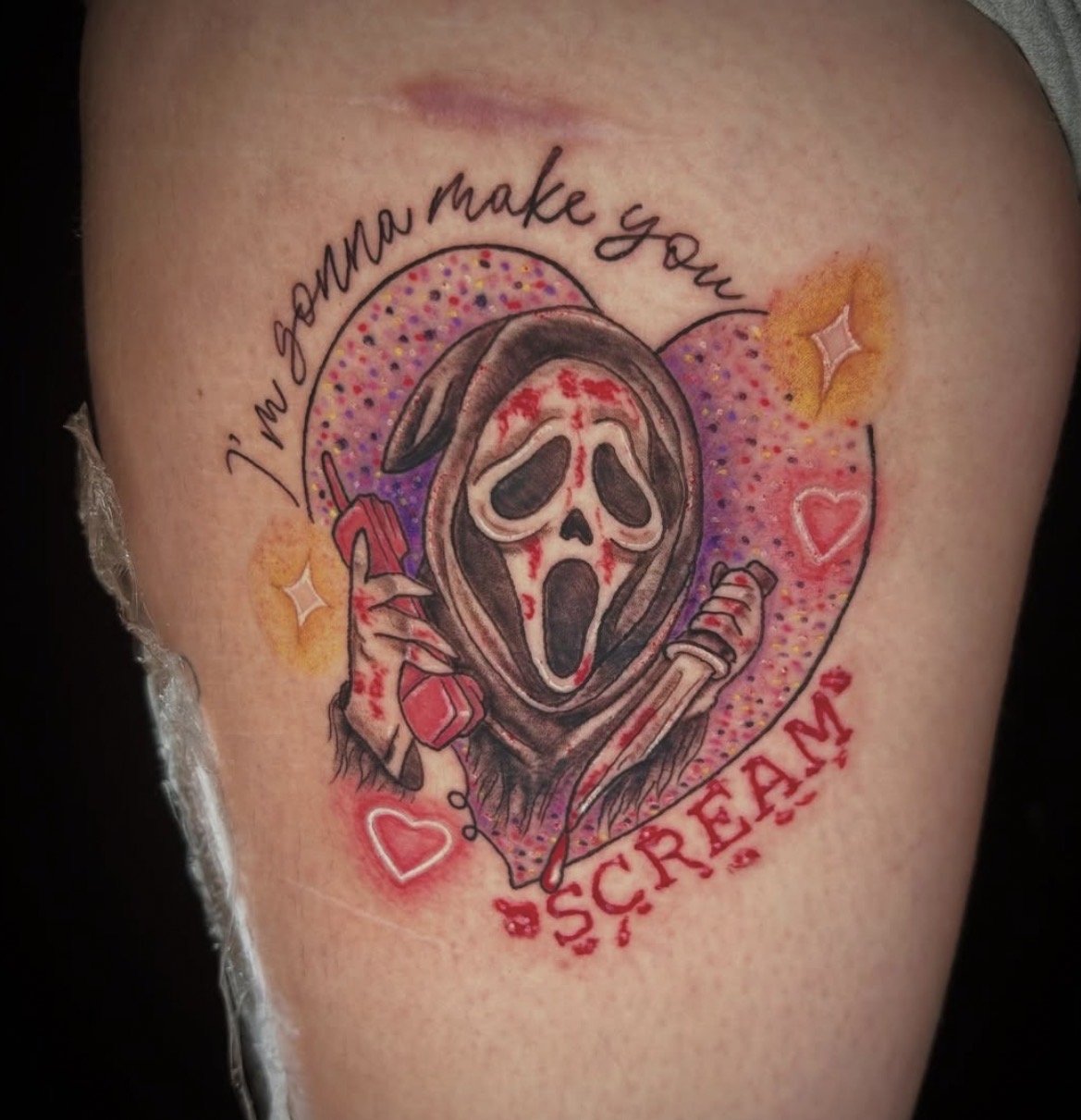 Tattoo of a skeleton wearing a hood, holding a phone, with the words 'I'm Salma make you' and 'SCRÉAM' with decorative hearts, stars, and colorful dots in the background.