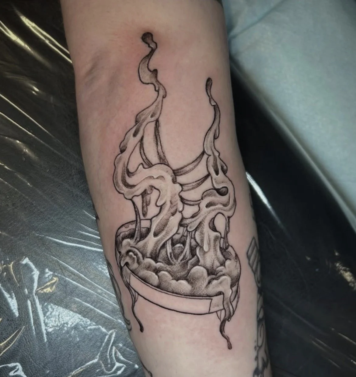 Black and gray tattoo of a coffee cup with steam rising.