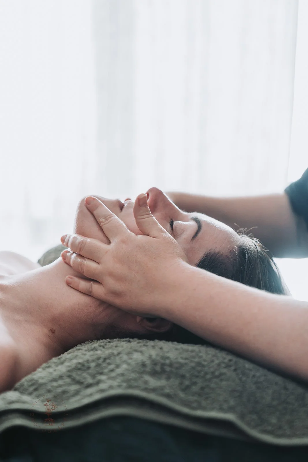 Person receiving a facial massage in a spa setting, lying down with eyes closed.