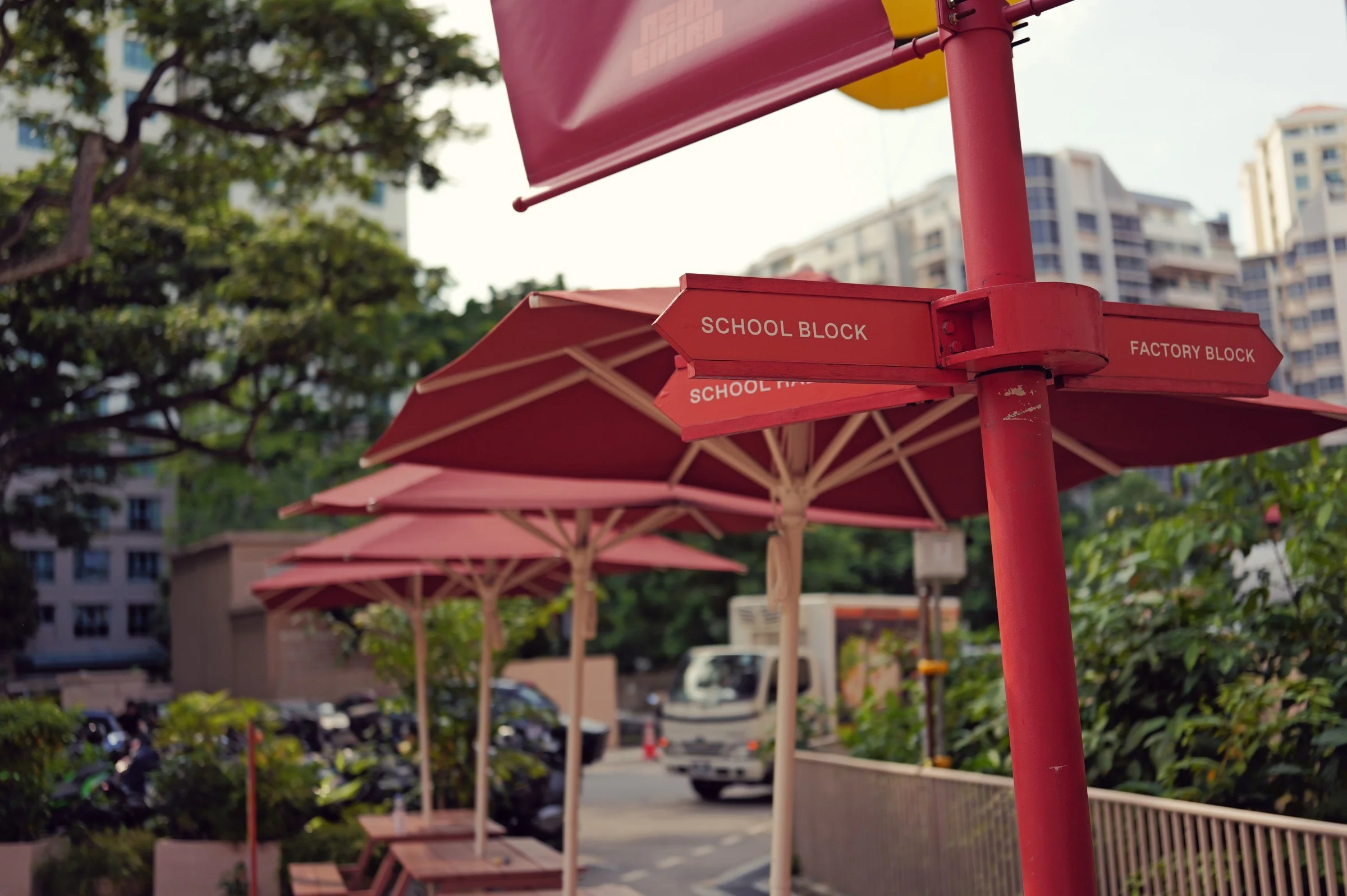 Red School Block umbrellas among greenery at New Bahru.