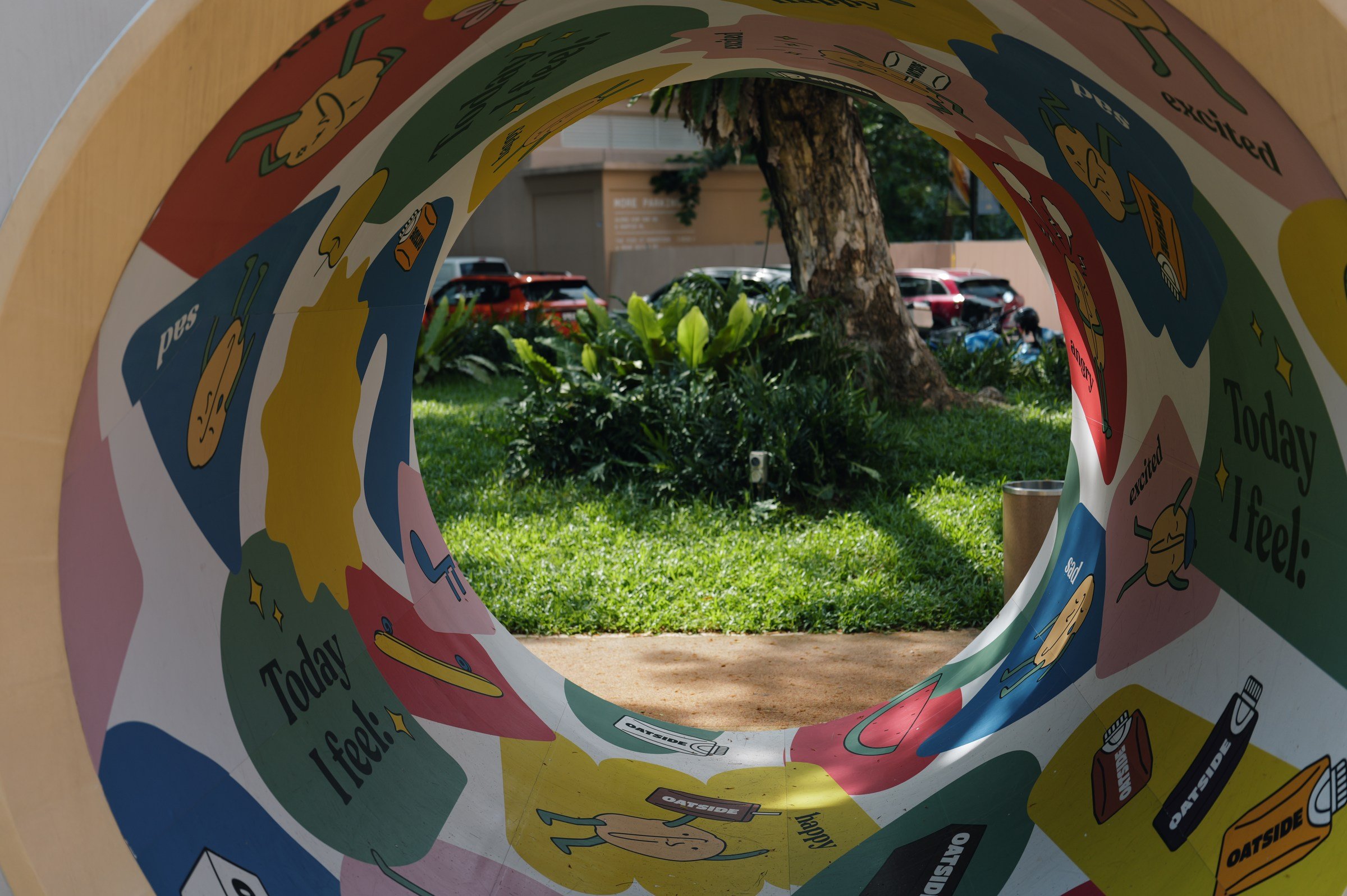 Colourful circular playground opening framing greenery at New Bahru.