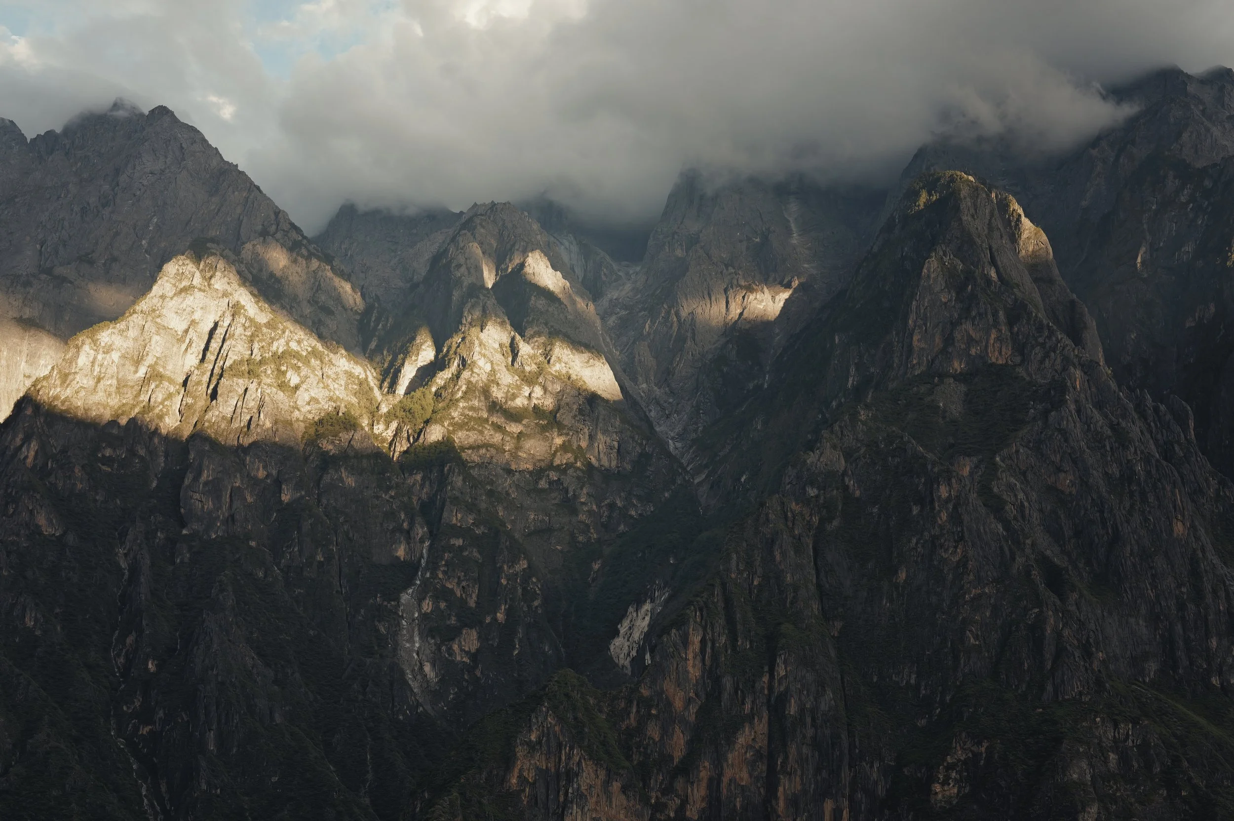Light breaking through clouds over the jagged peaks of Tiger Leaping Gorge, photographed with a Leica Q3 43