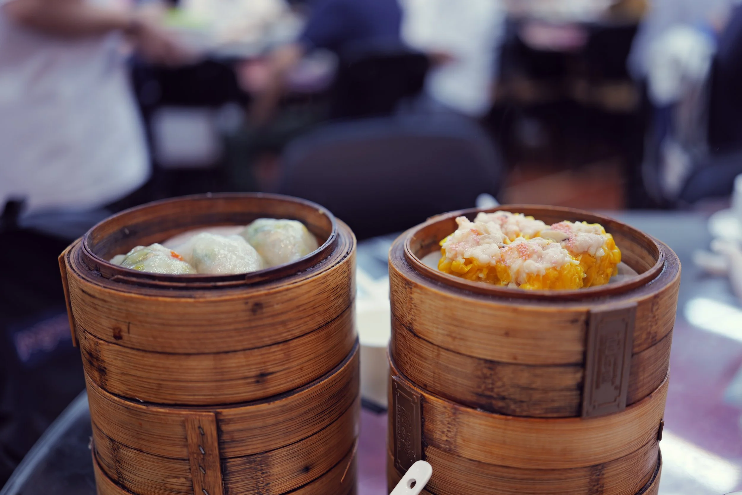 Close-up of two bamboo steamers filled with dim sum, placed on a table in a restaurant setting.