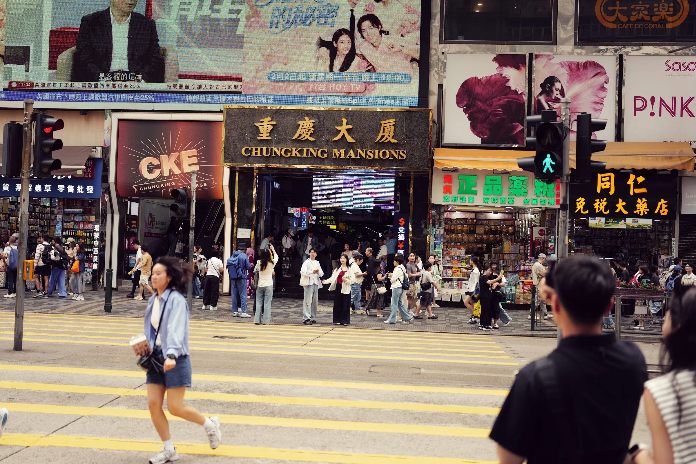 Illuminated Chungking Mansions signage and evening street activity in Tsim Sha Tsui, Hong Kong.