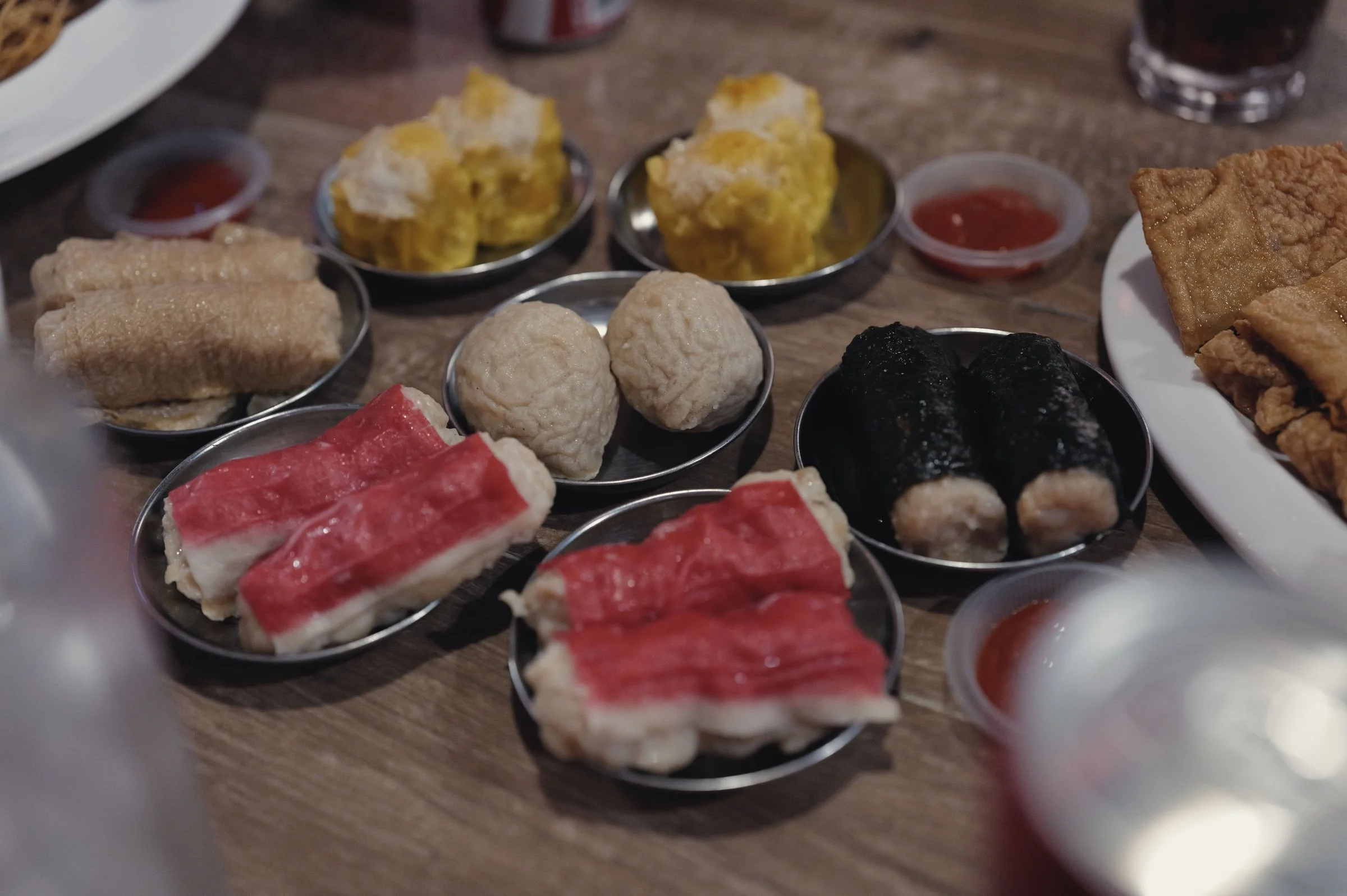 Colourful dim sum and dipping sauce fill small plates on a table.