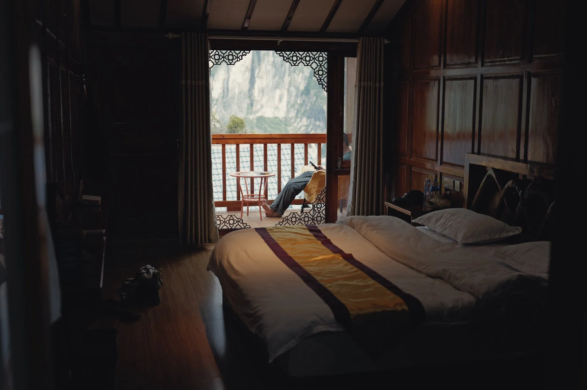Wooden guest room at Qi Feng Shan Homestay, with twin beds opening onto a balcony overlooking Tiger Leaping Gorge.