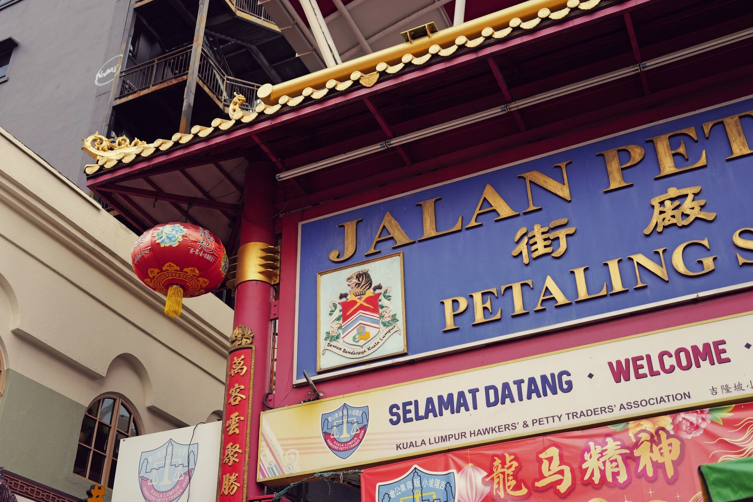 A red-and-gold gateway sign marks Jalan Petaling beneath hanging lanterns.