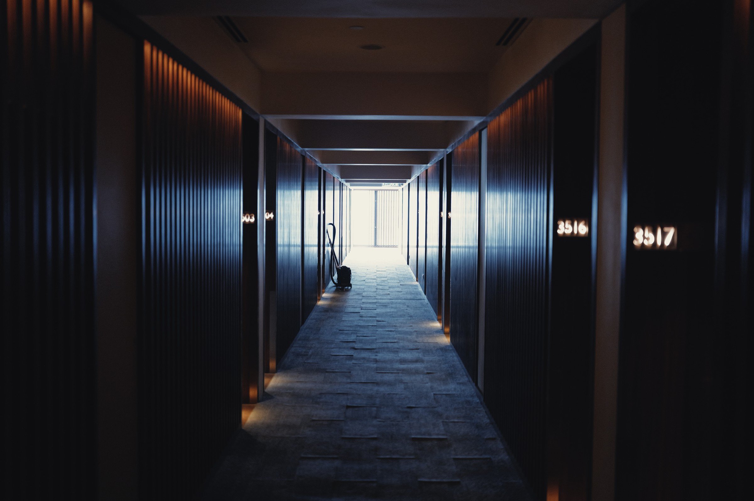 A dark corridor leads toward a bright window at its far end.