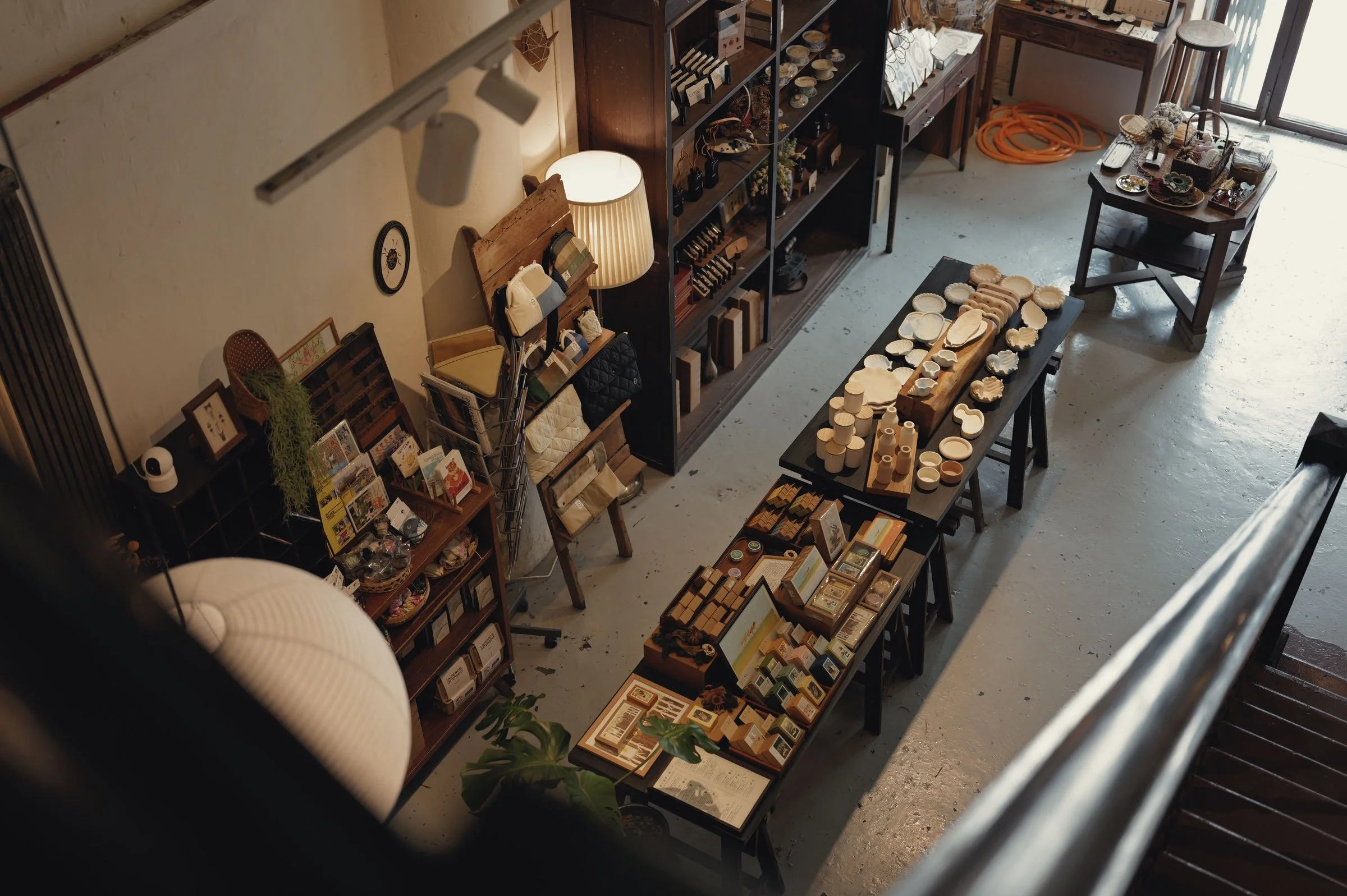 Ceramics and small objects line tables in a warmly lit shop.