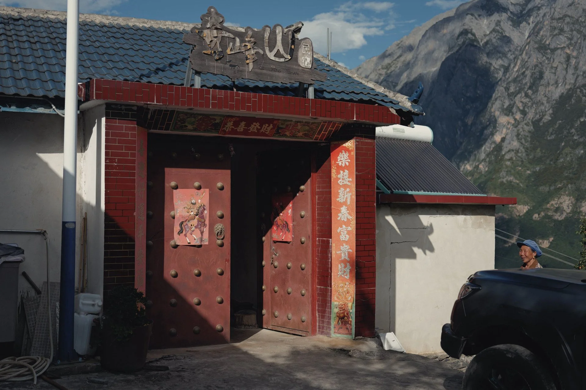 Traditional red entrance gate of Qi Feng Shan Homestay beneath the mountains of Tiger Leaping Gorge, Yunnan.