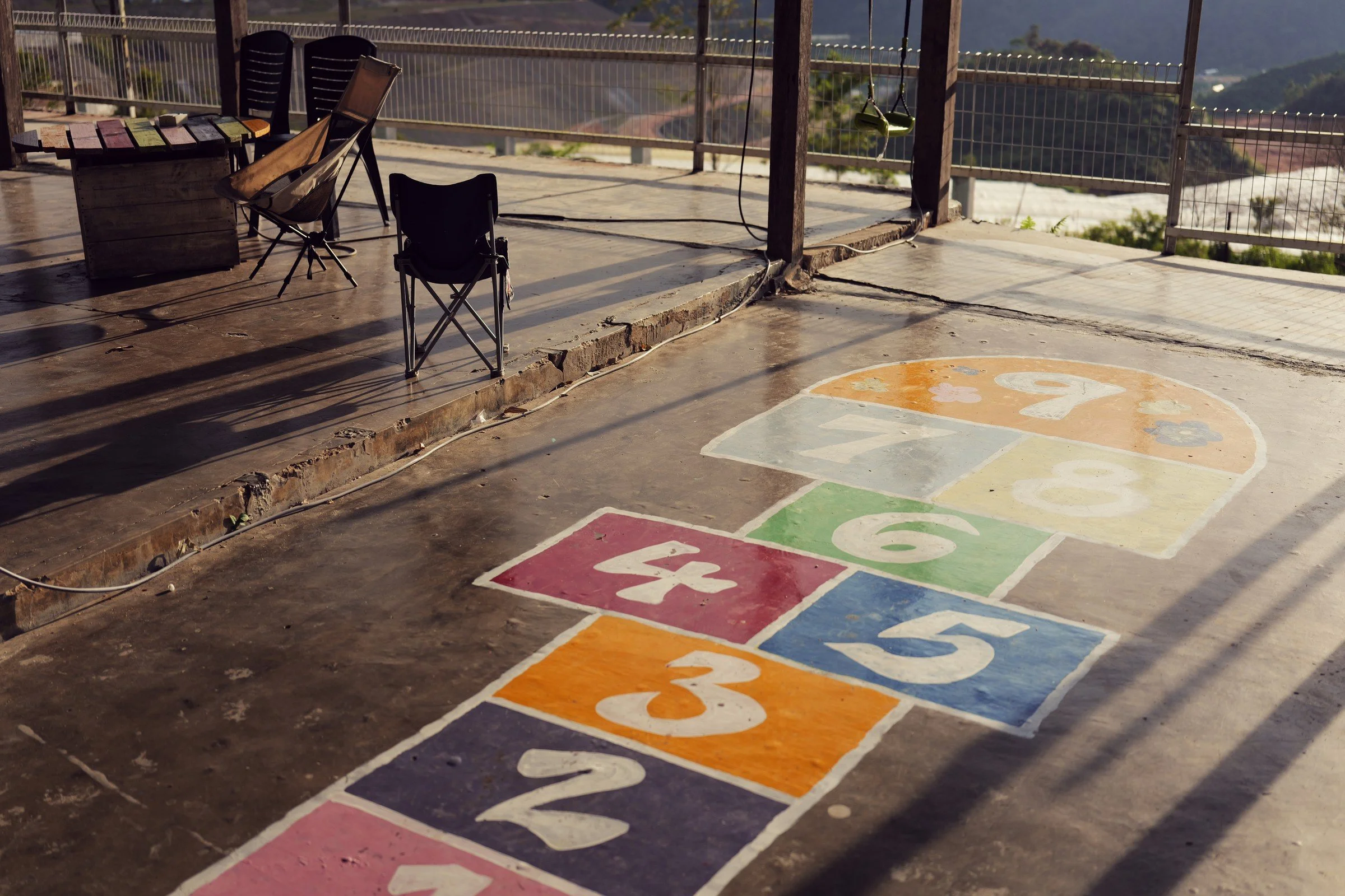 A colorful hopscotch grid catches the light beside chairs on a sheltered terrace.