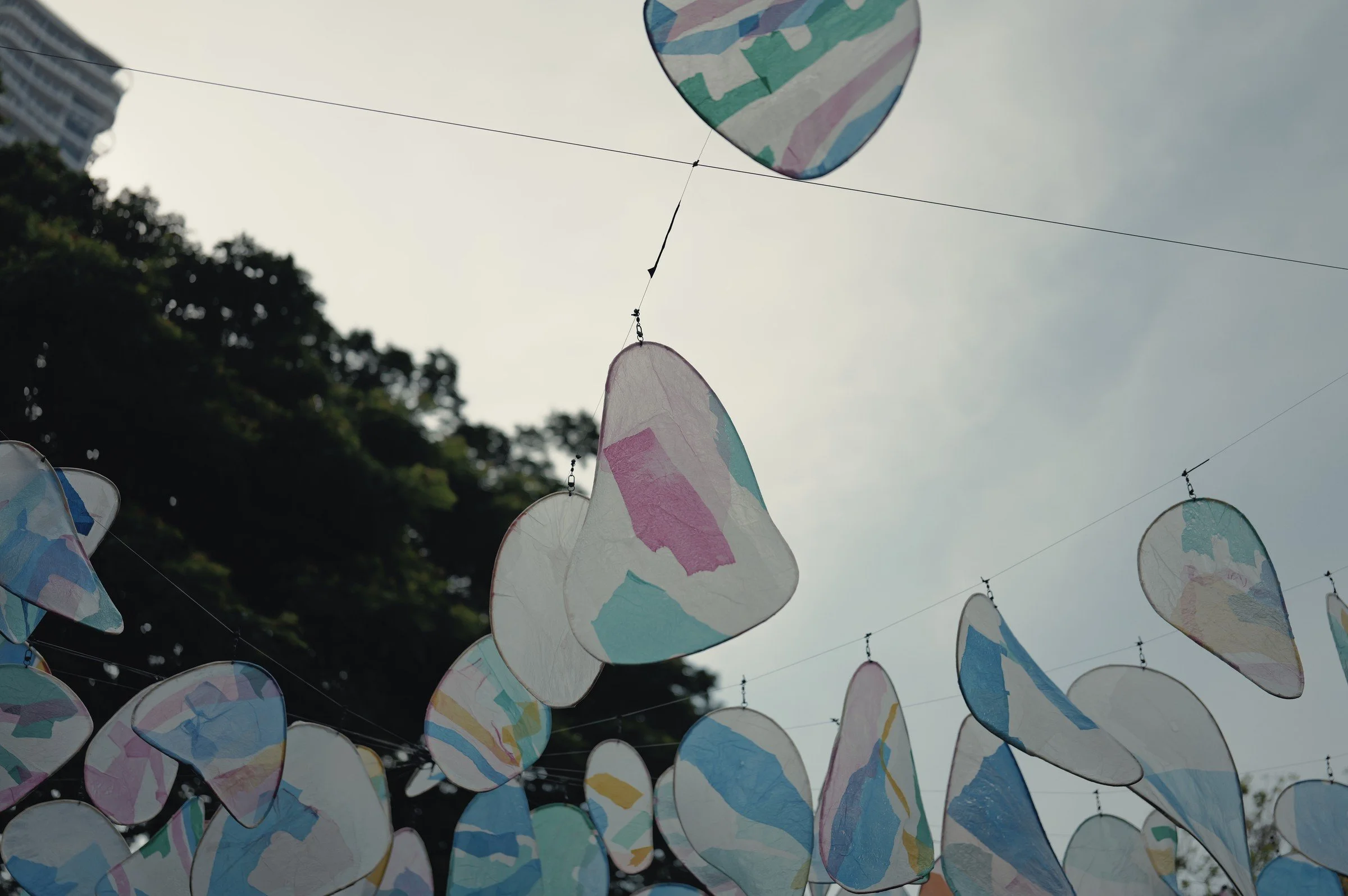 Translucent pastel decorations hang against a cloudy sky.