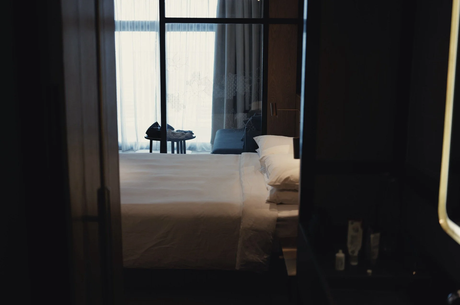 Guest room at Alila Bangsar in Kuala Lumpur, with a bed beside a tall window overlooking the city.