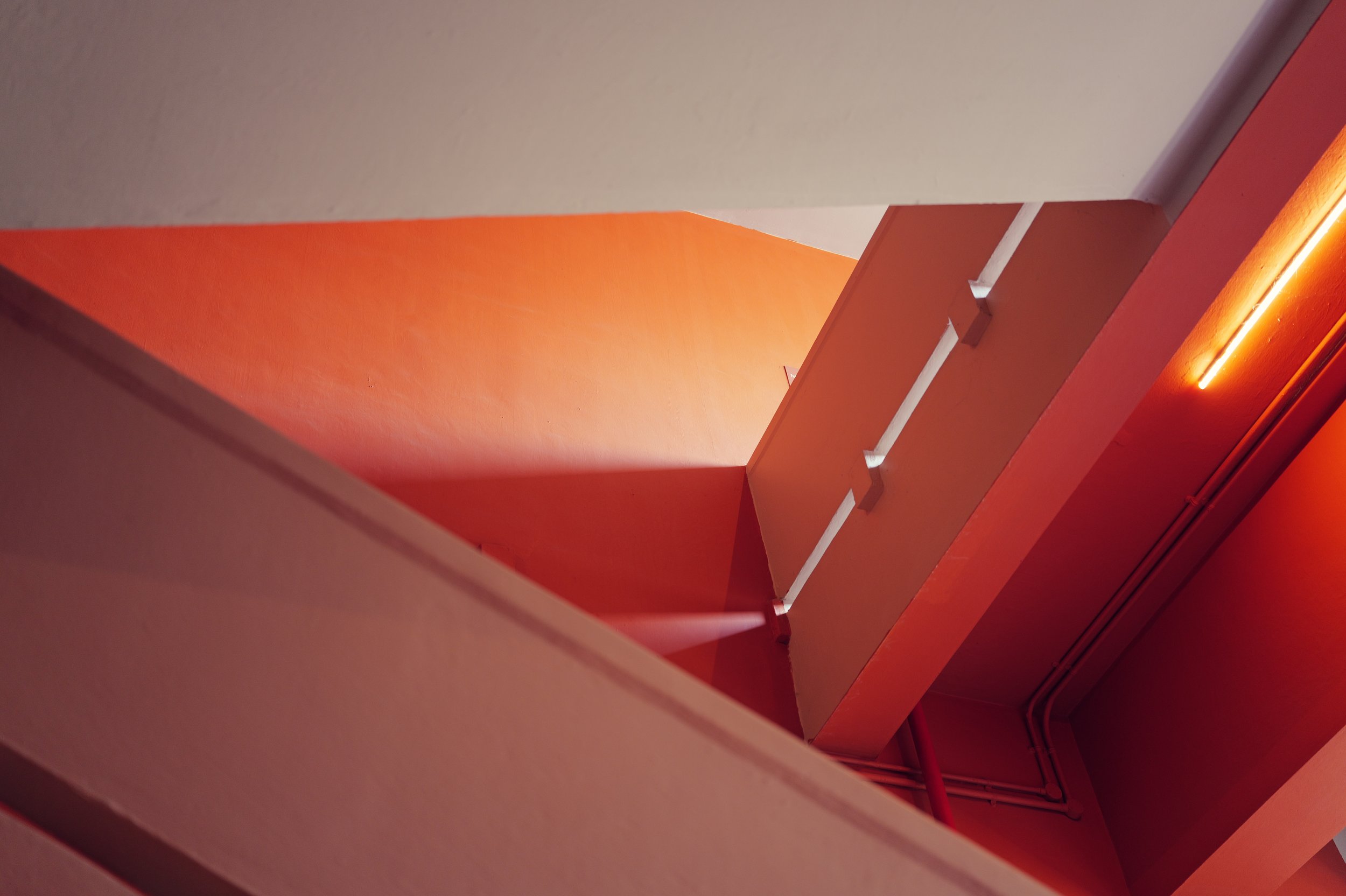 Abstract photo of orange and white architectural structures with glowing orange lighting, viewed from below.