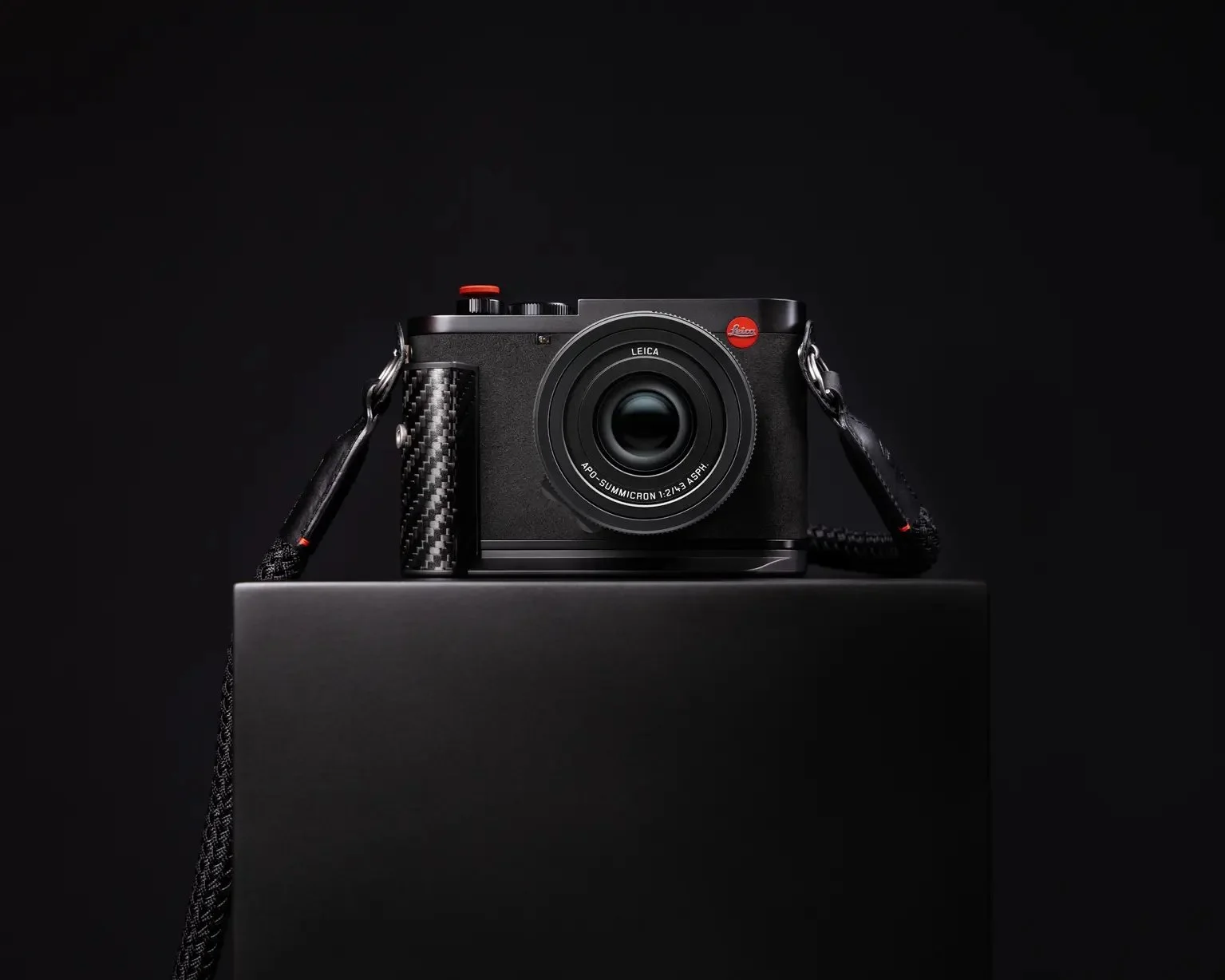Leica Q3 43 Formula 1 Edition on a black plinth, showing its carbon-fibre grip, black body and red shutter release.