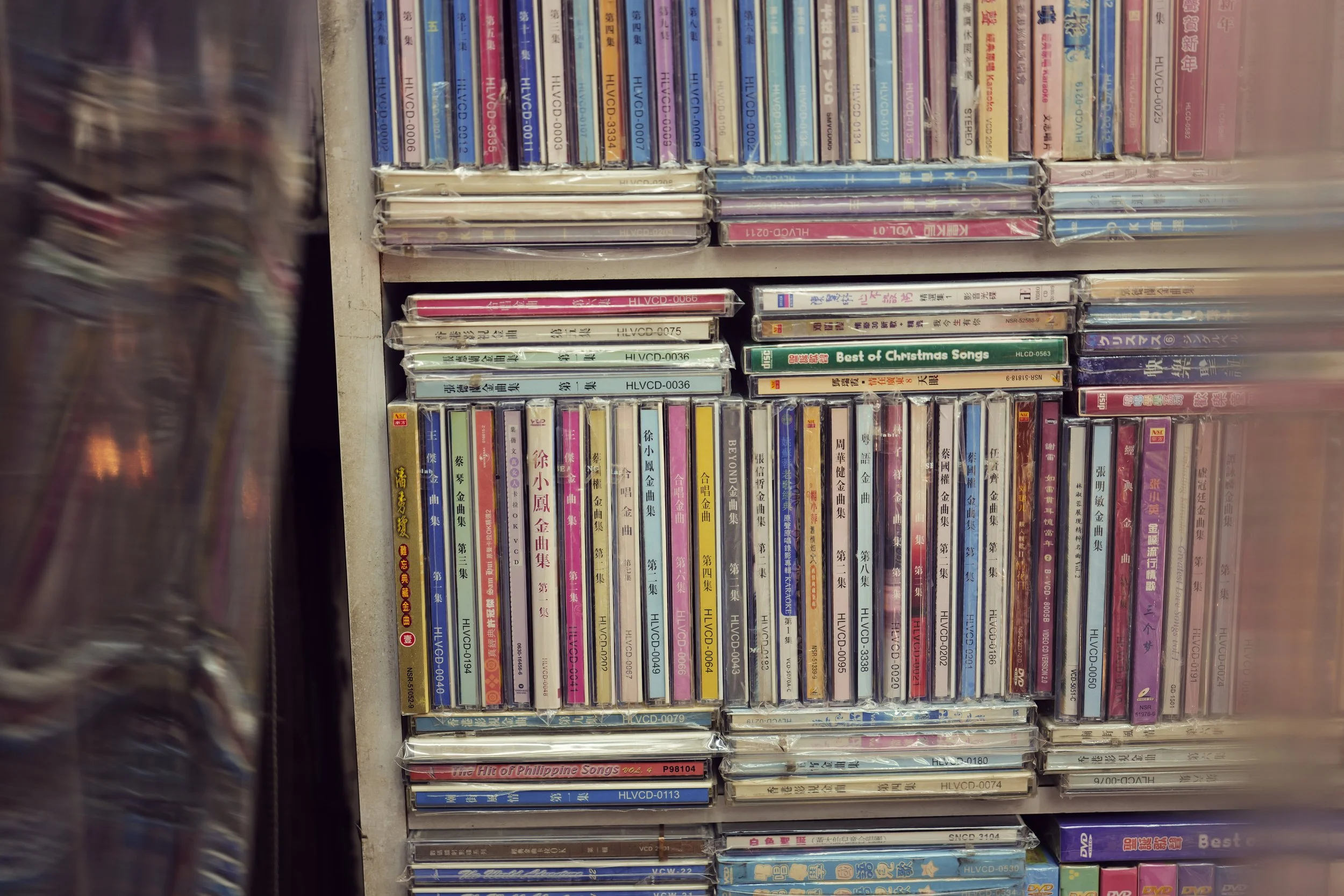 Shelf filled with Asian music CDs and DVDs, some still in plastic wrap.