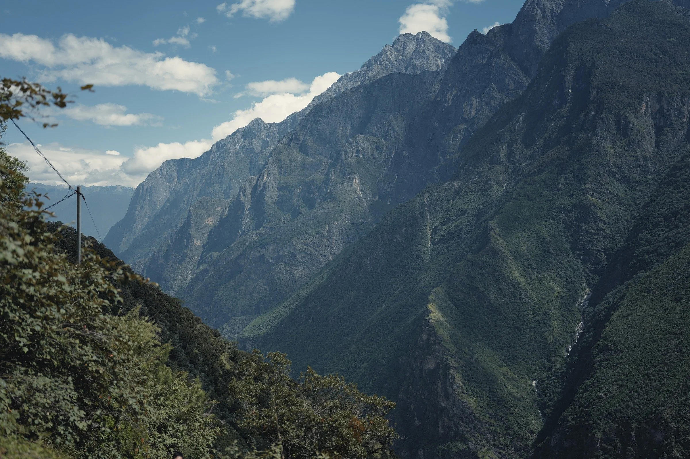 A sunlit mountain wall rises above the deep valley in Tiger Leaping Gorge, Yunnan.