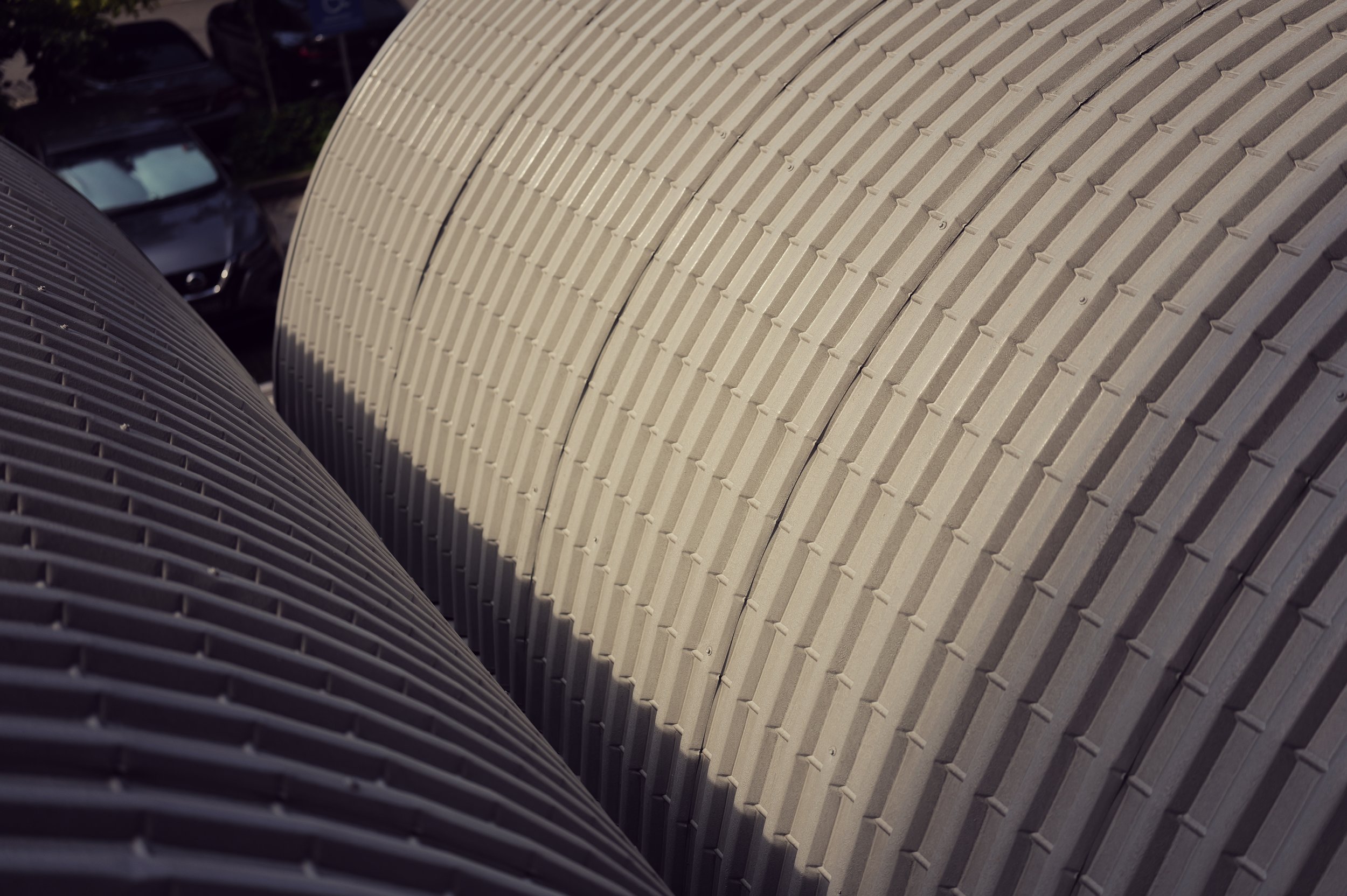 Close-up of the curved exterior of a building with a grid-like pattern of vents or panels.