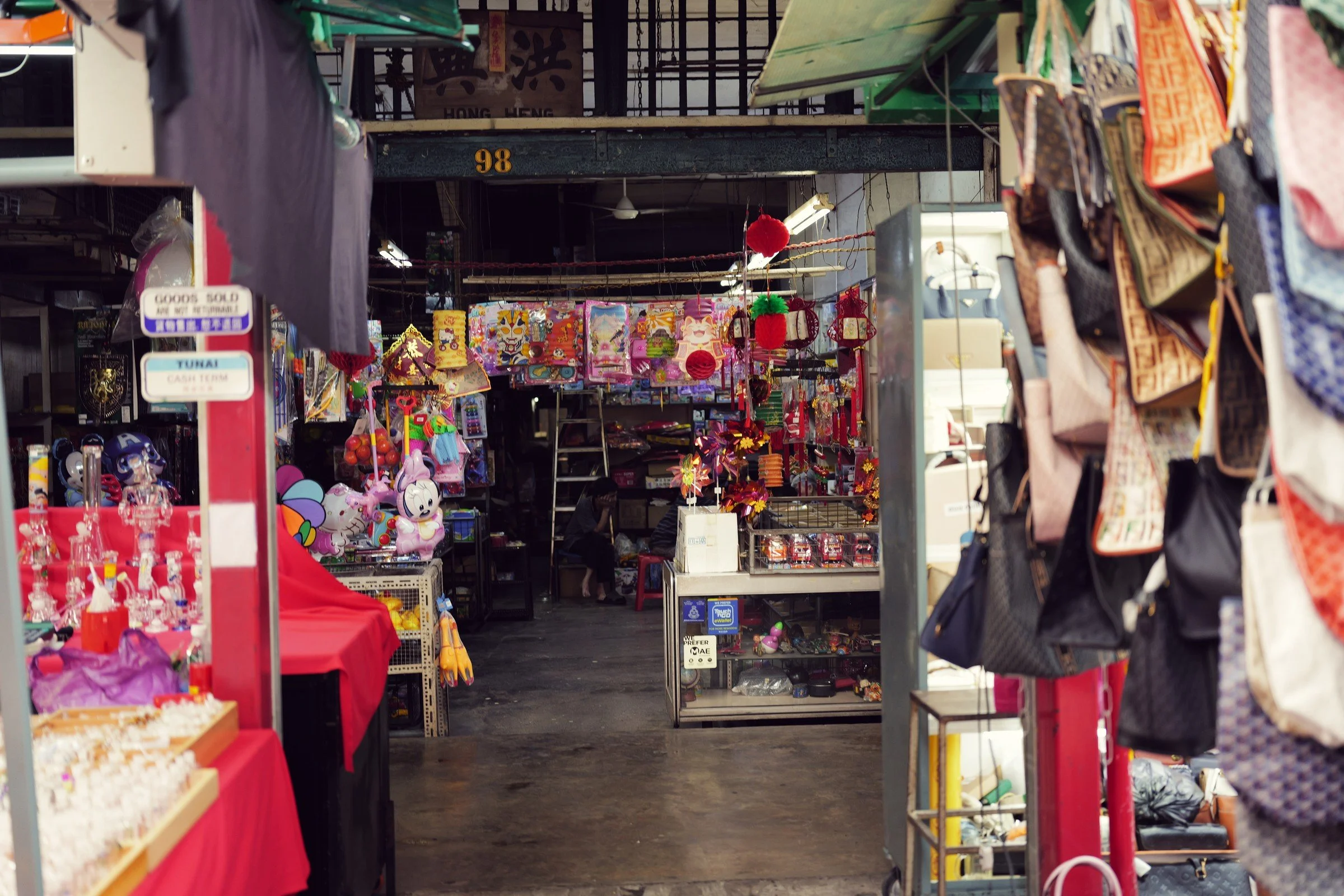 A narrow shop entrance is framed by hanging bags and colorful merchandise.